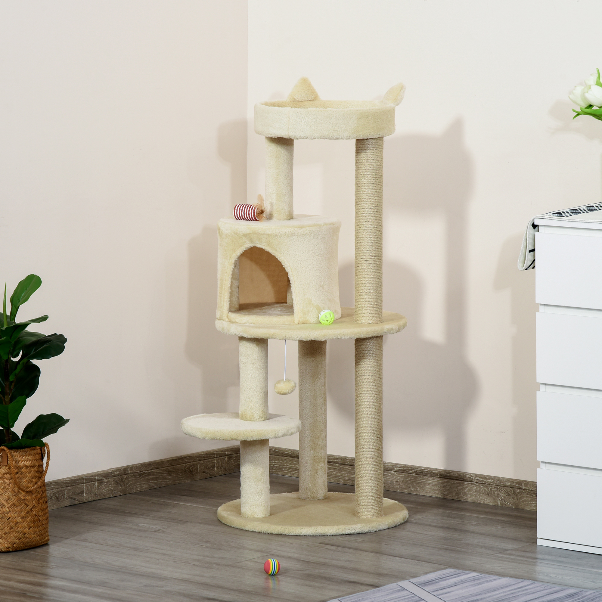Albero per gatti beige a più livelli con pali per tiragraffi, piattaforme, una cuccia e giocattoli pendenti.