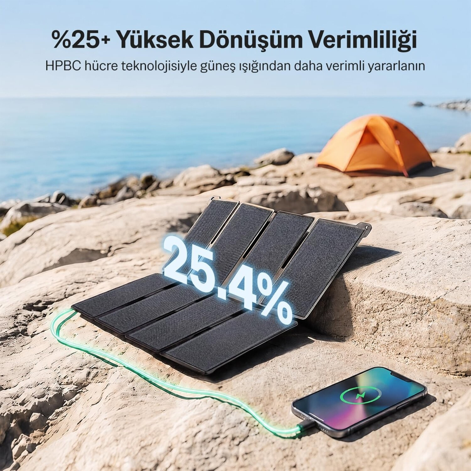 Kayalar üzerindeki taşınabilir güneş paneli, arka planda deniz ve çadırla bir akıllı telefonu şarj ediyor.