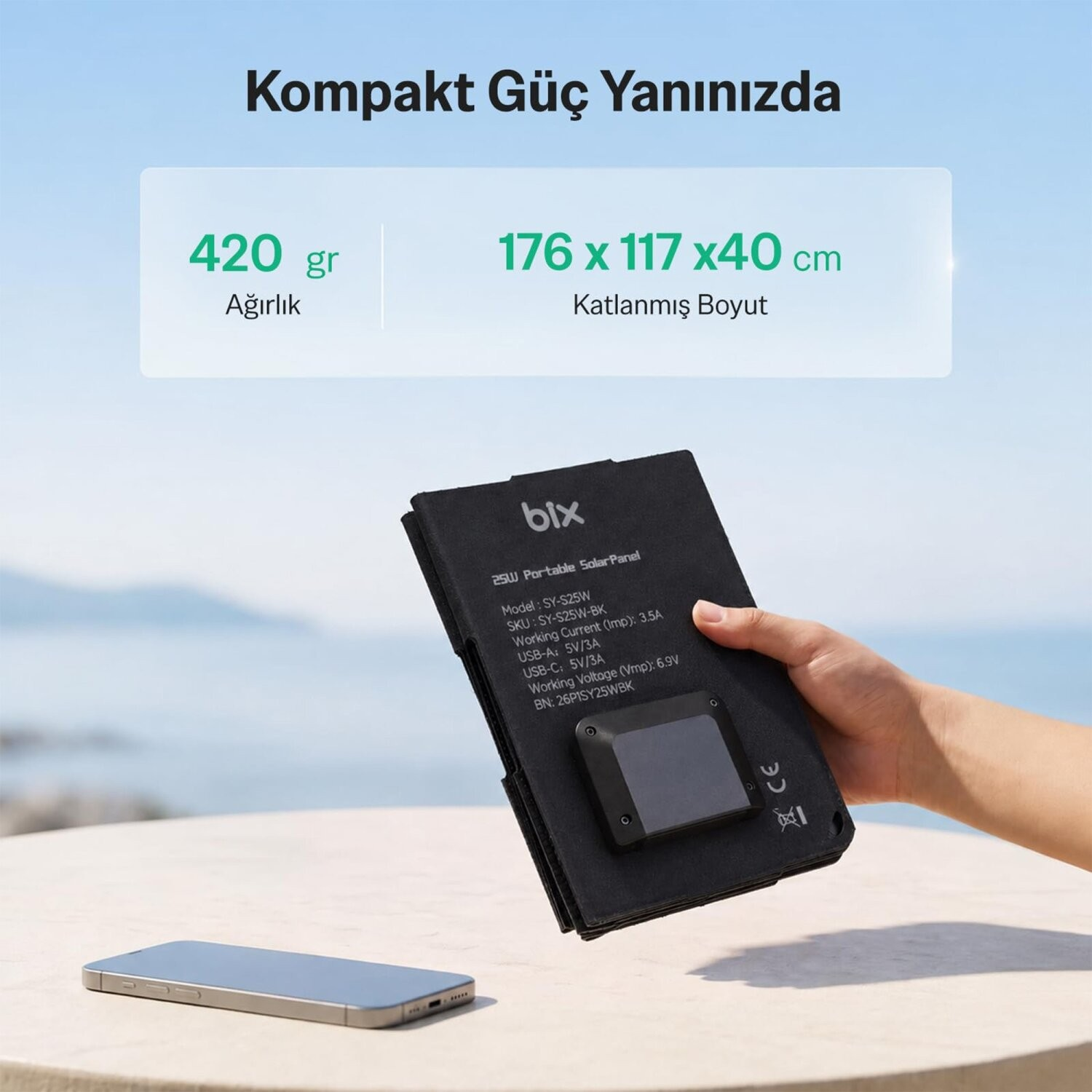 El, akıllı telefonlu masa üzerinde katlanabilir bix güneş panelini tutuyor.