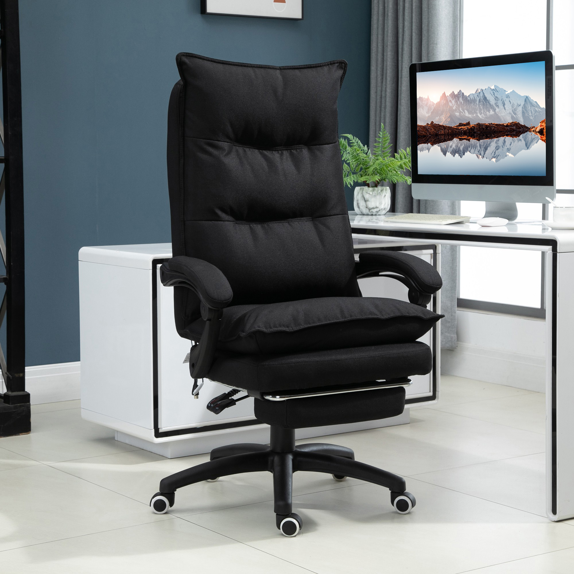 Sedia da ufficcio ergonomica nera con poggiapiedi davanti a una scrivania bianca.