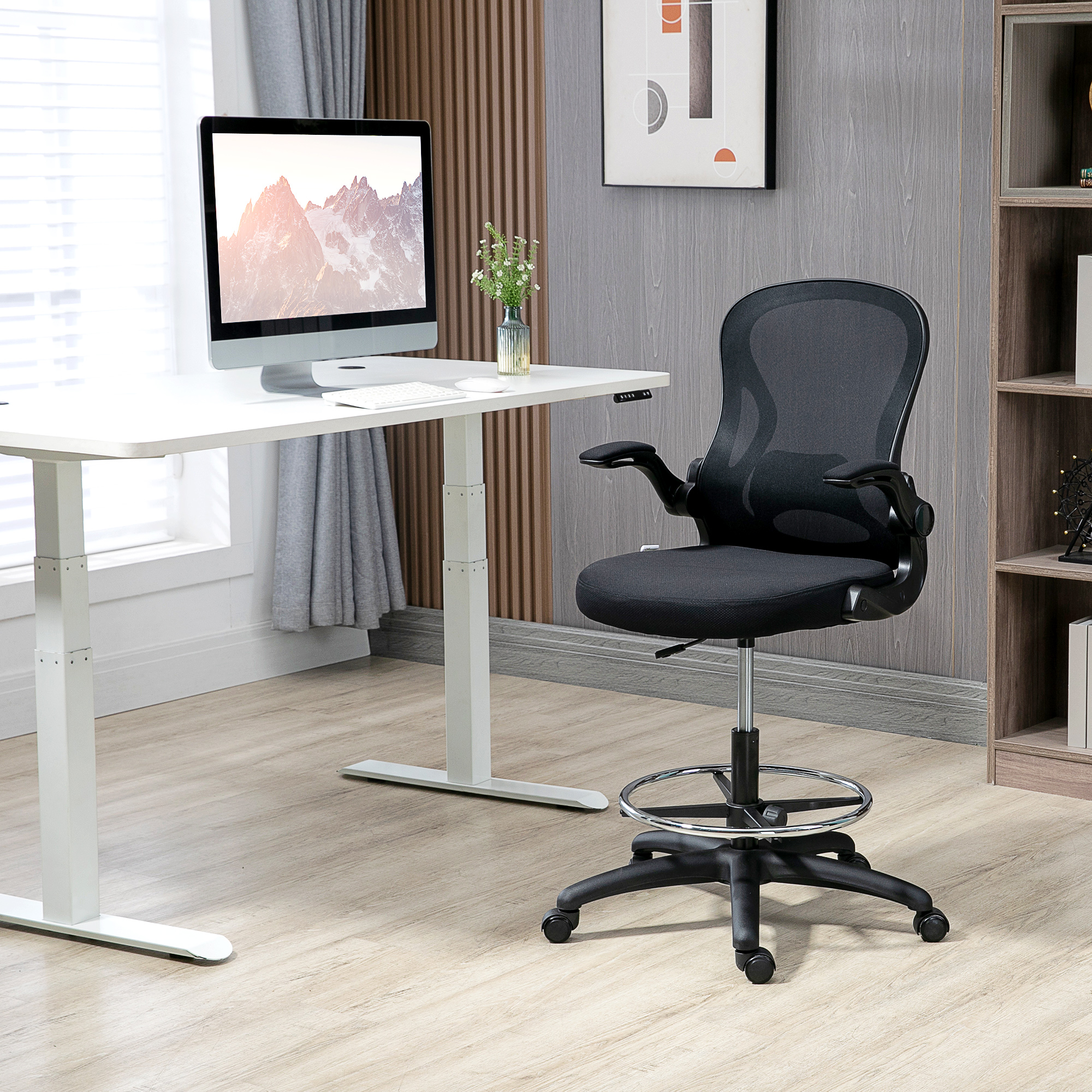 Una sedia da ufficio ergonomica nera con poggiapiedi davanti a una scrivania bianca regolabile in una stanza moderna.