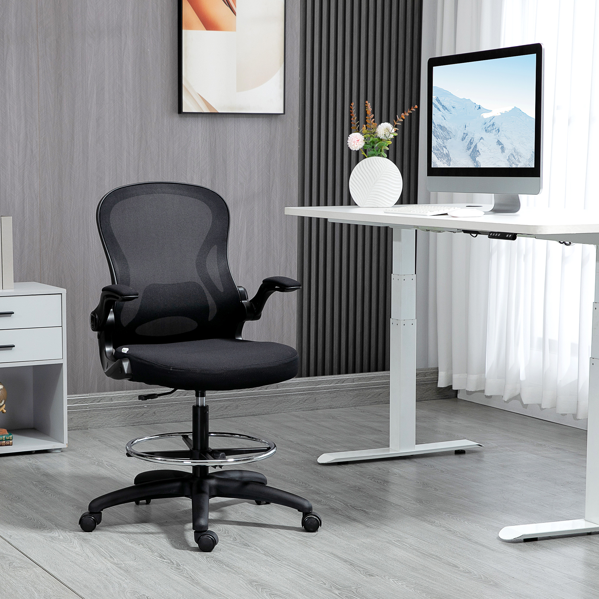 Una sedia da ufficio ergonomica nera con poggiapiedi davanti a una scrivania elegante con computer.