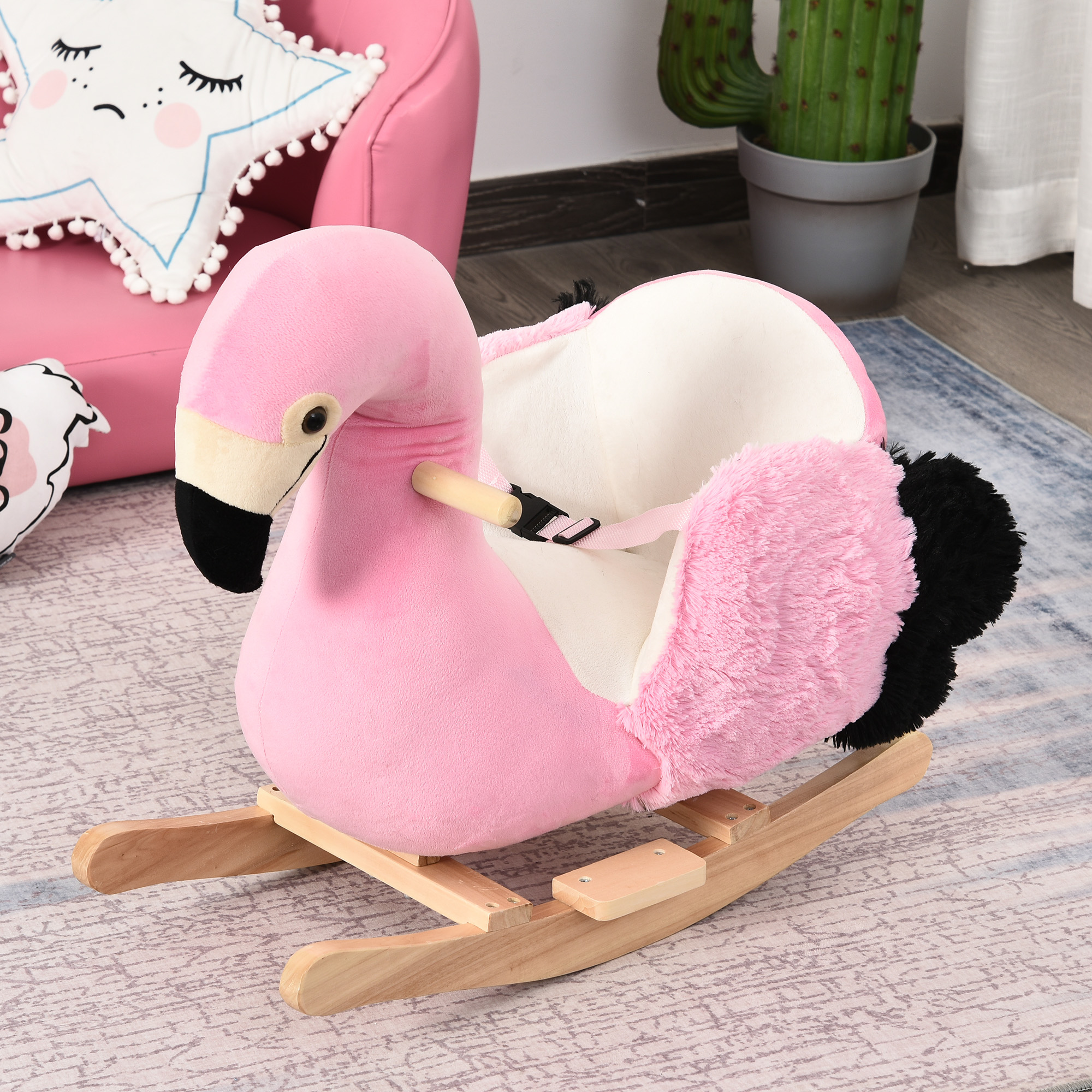Un dondolo a fenicottero in peluche rosa con basi di legno si trova su un tappeto blu e bianco.