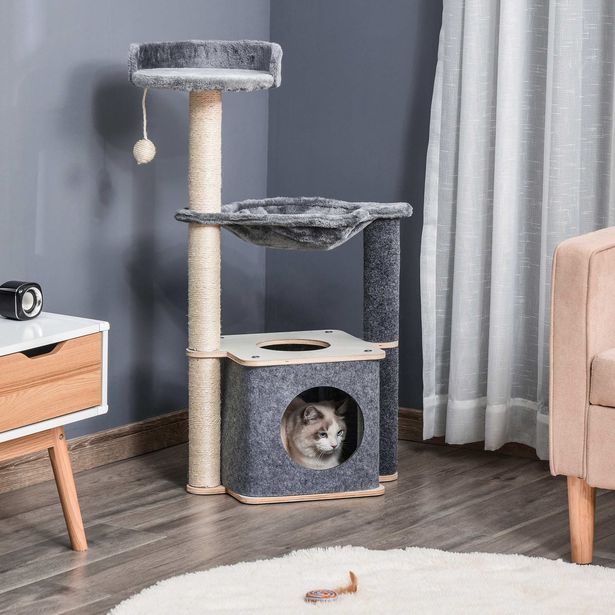 Un gatto fa capolino dalla cuccia grigia di un tiragraffi multistrato.