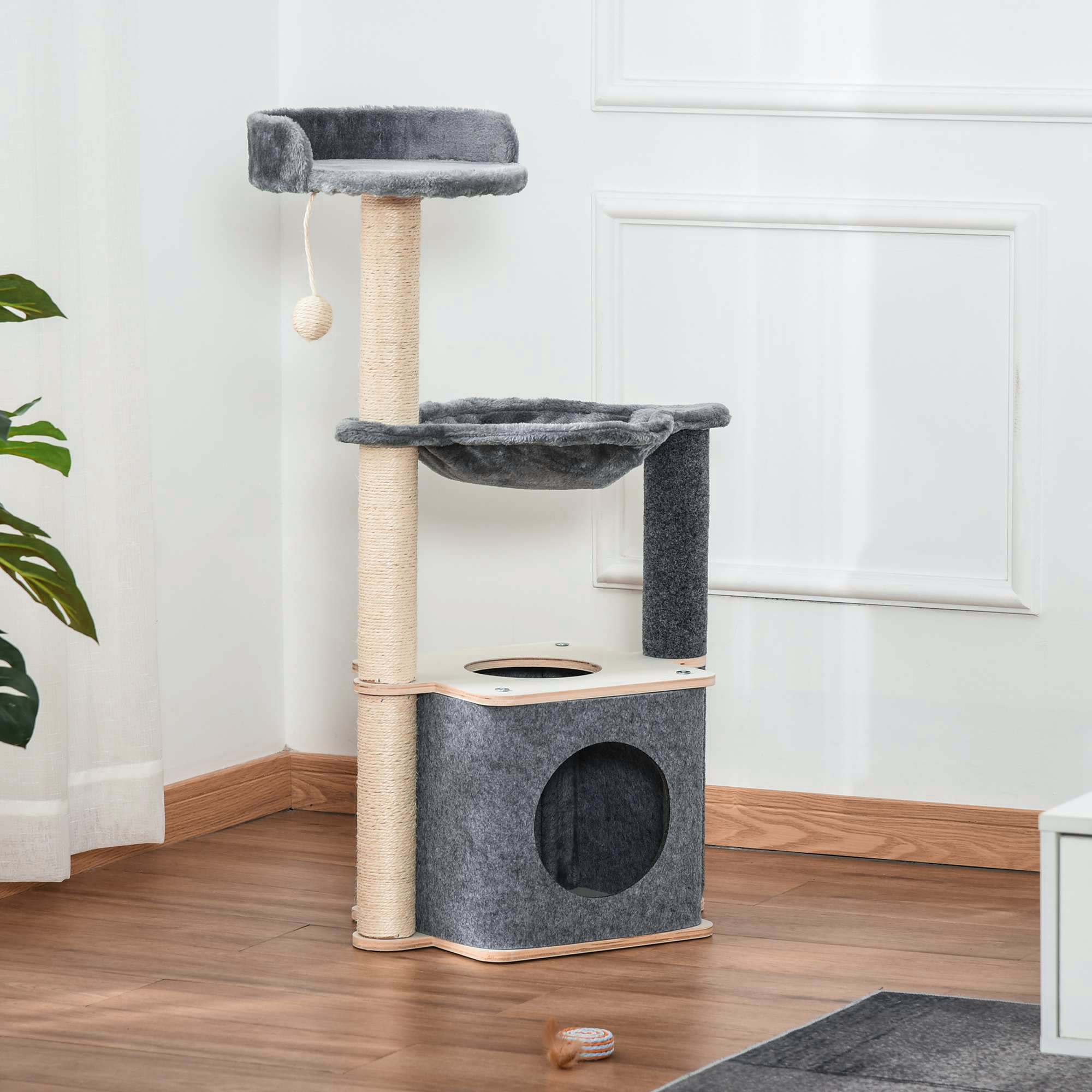Albero per gatti grigio e in legno con cuccia, amaca e pali in sisal in una stanza luminosa.