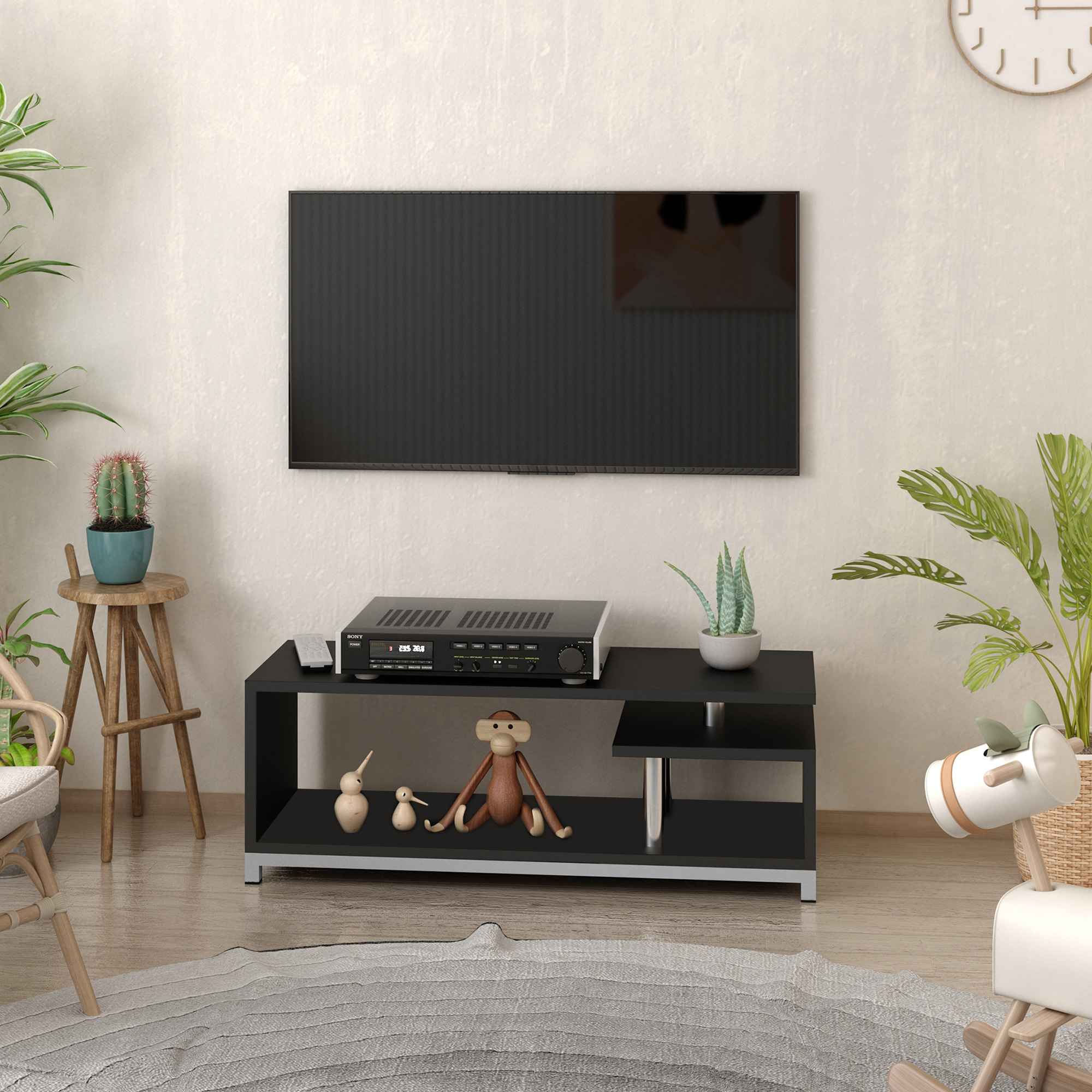 Soggiorno con TV nera a parete, mobile TV, piante e giocattoli.