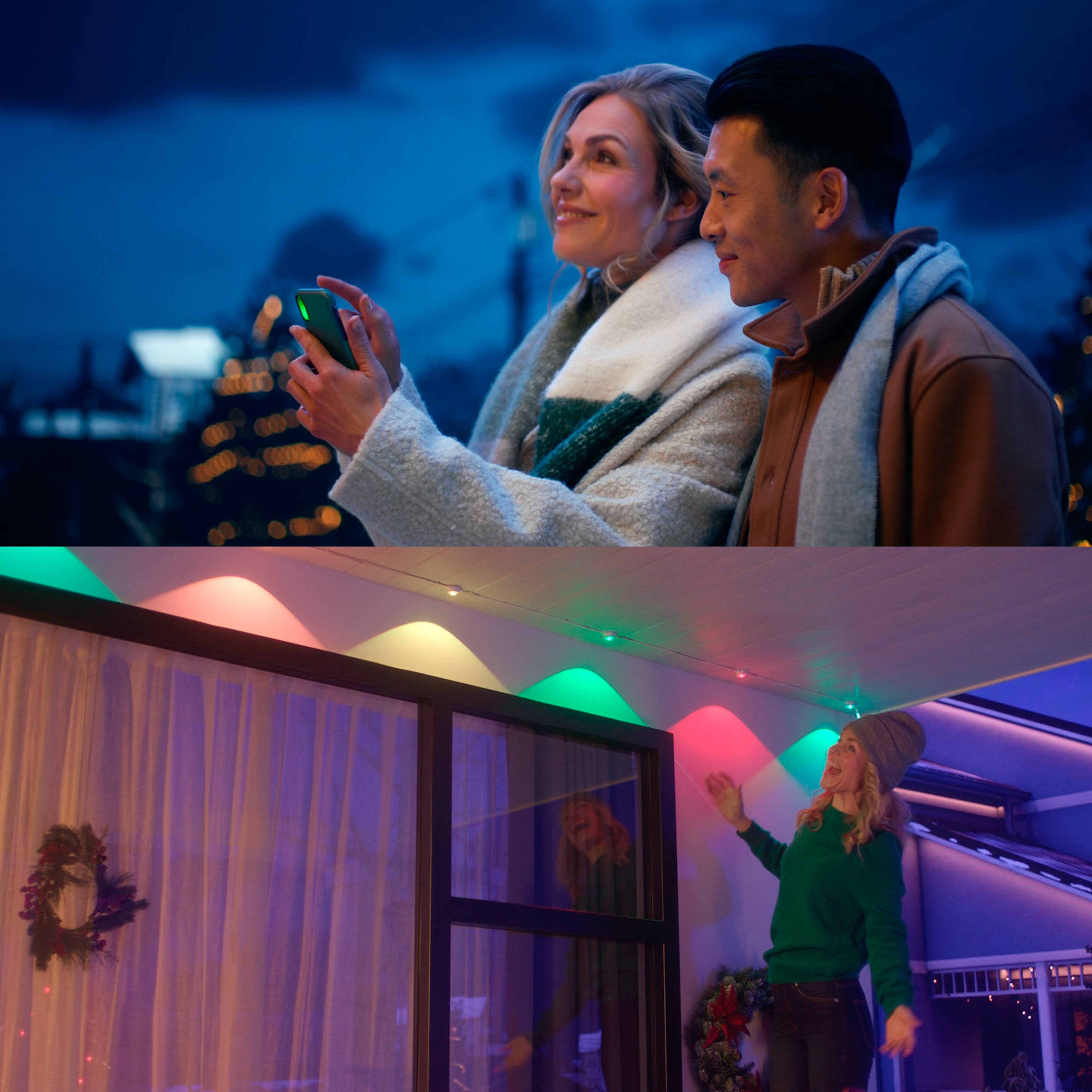 Una coppia con abiti invernali usa uno smartphone all'aperto mentre luci colorate illuminano una casa.