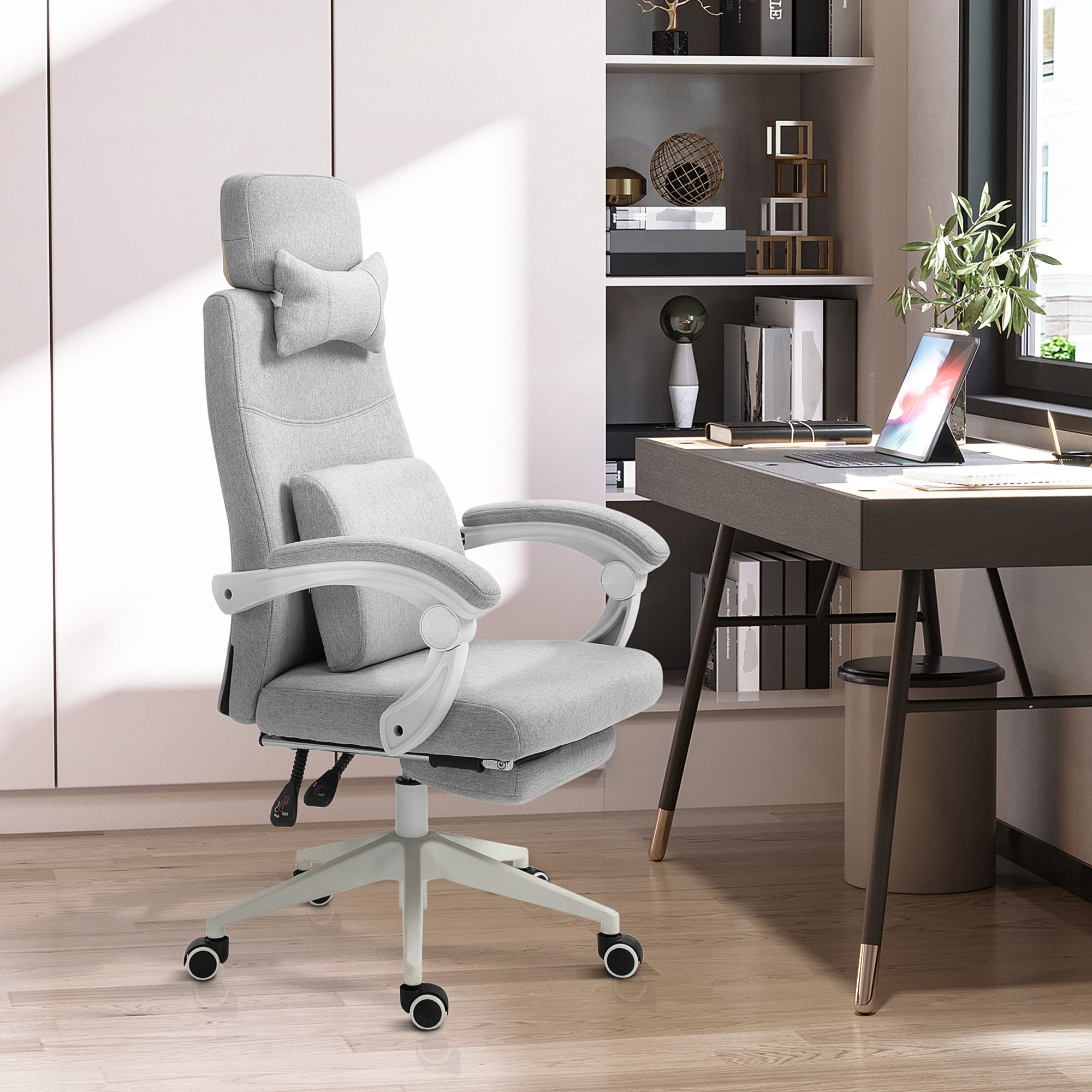 Una sedia ergonomica grigia si trova in un ufficio luminoso davanti a una scrivania con laptop e libreria.