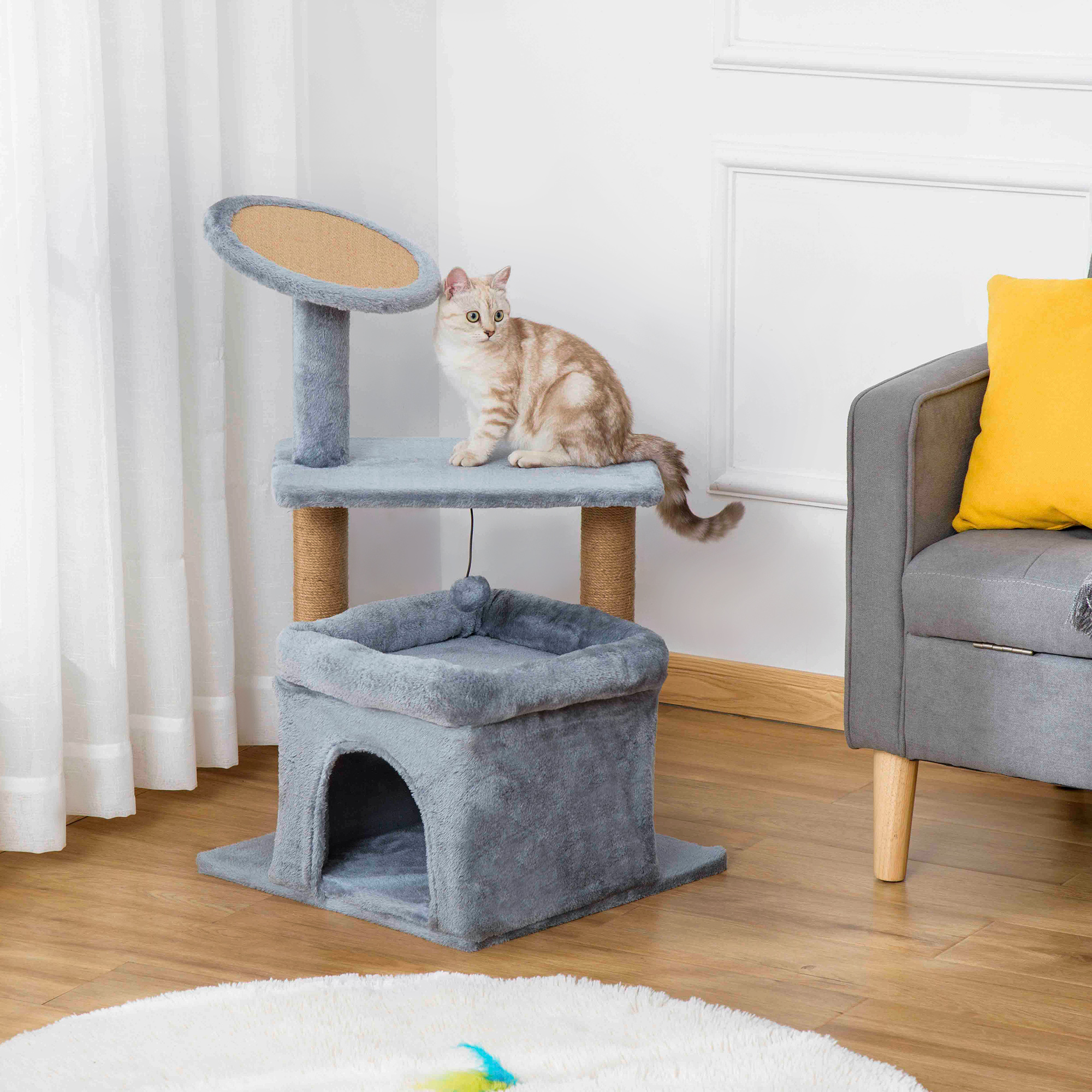 Un gatto beige siede su un tiragraffi grigio a più livelli in una stanza luminosa.
