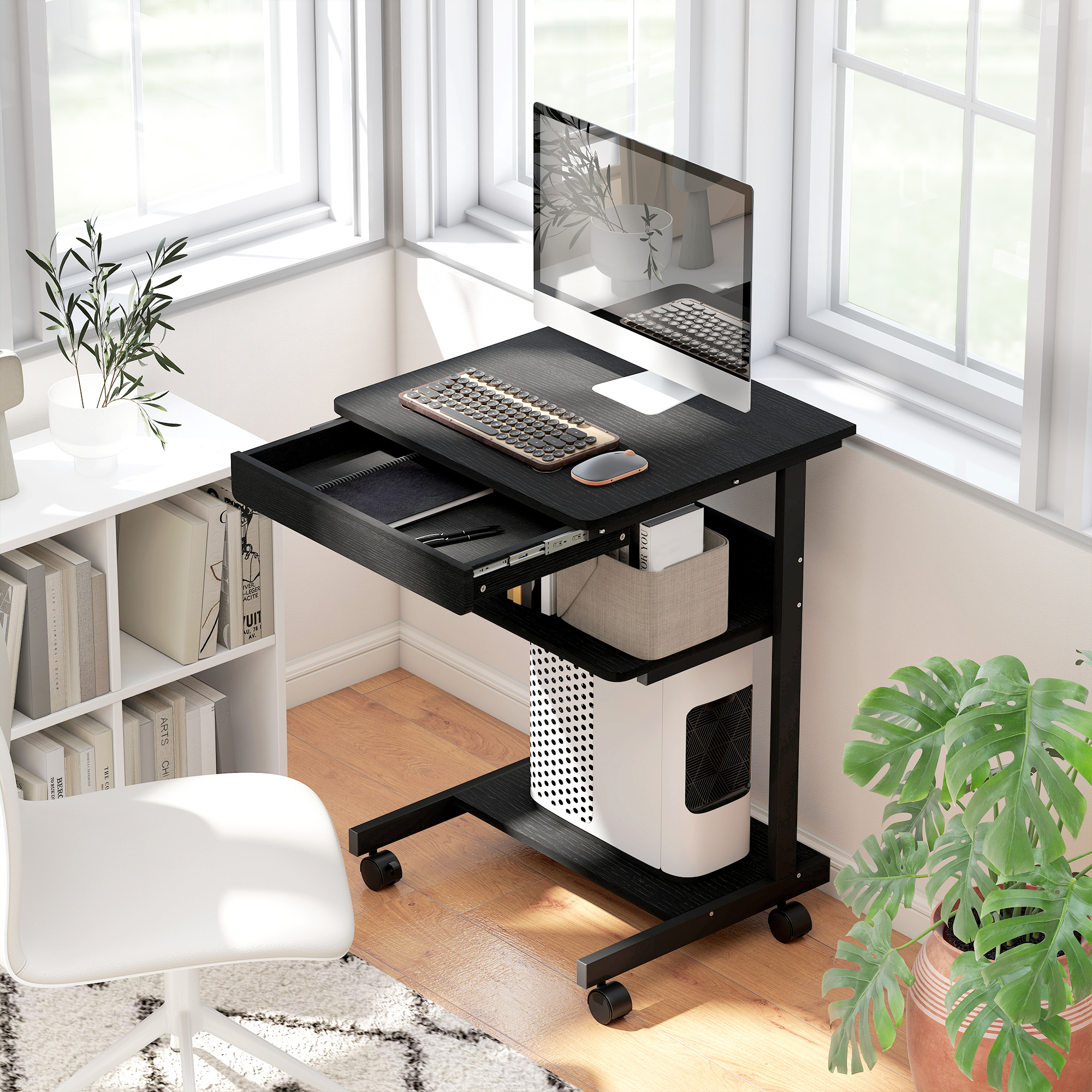 Una scrivania per computer nera con ruote, monitor, tastiera e cassetto aperto, posizionata in un angolo luminoso.
