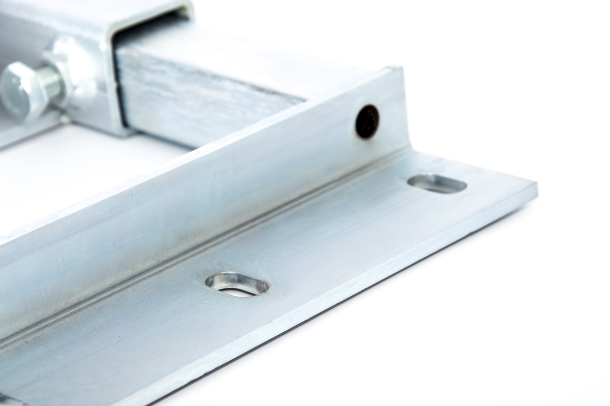 Nahaufnahme einer silbernen Metallhalterung mit Schraublöchern auf weißem Grund.