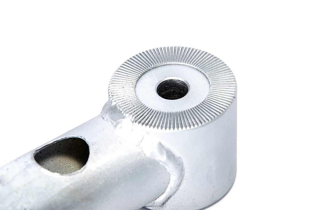 Nahaufnahme eines silbernen Metallteils mit geriffeltem Kreis und Bohrung.