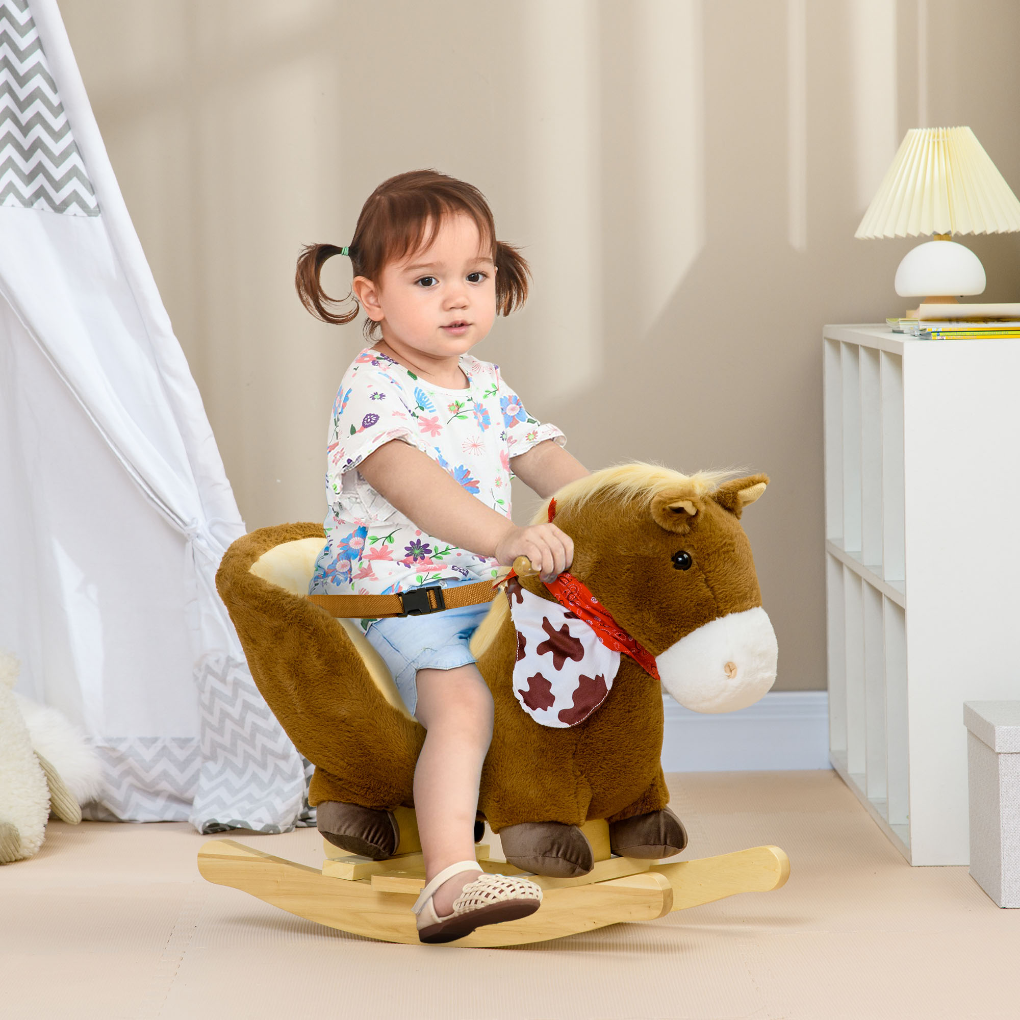 Bambina con le treccine cavalca un cavallo a dondolo di peluche in una stanza.