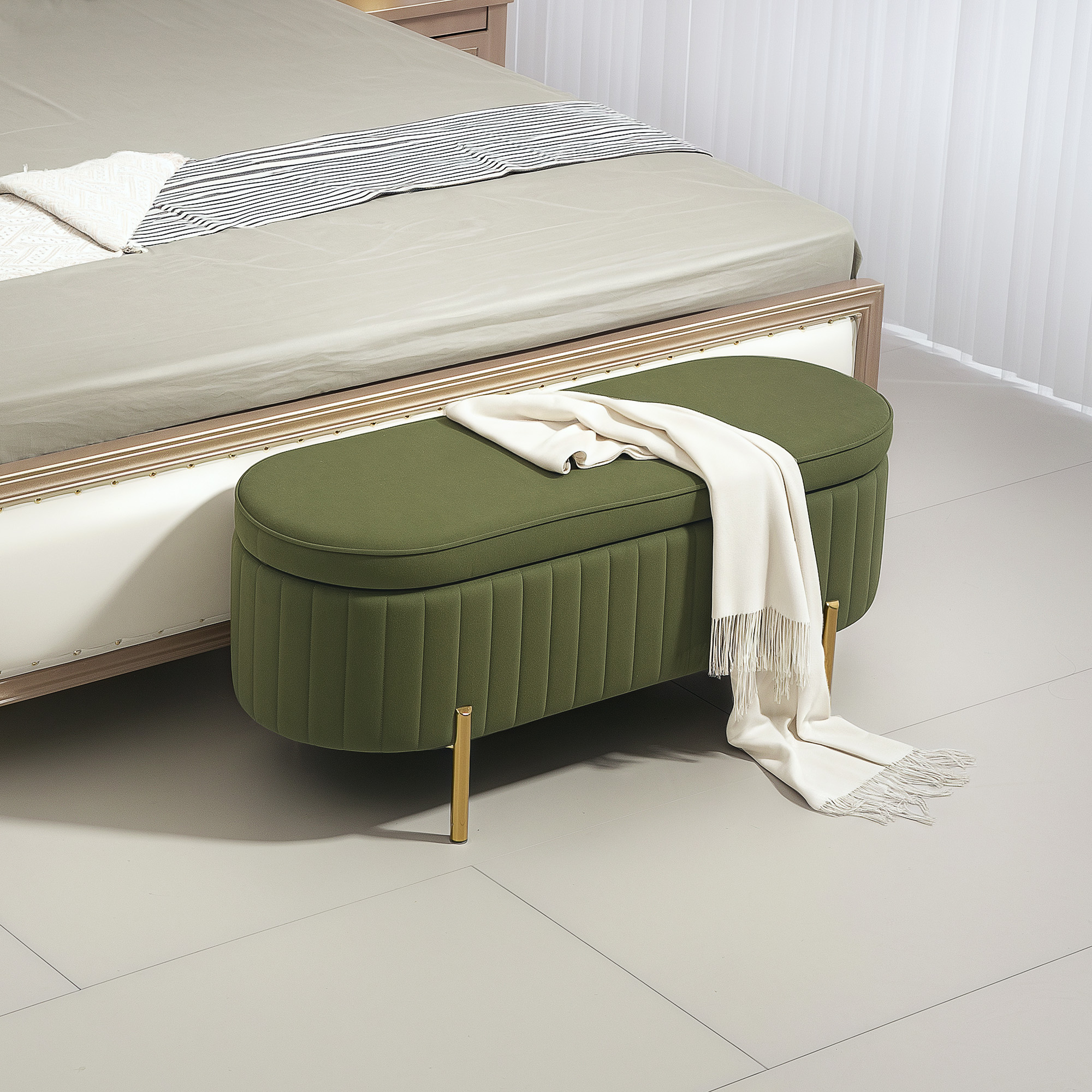 Una panca verde imbottita con gambe dorate e una coperta chiara si trova su un pavimento chiaro davanti a un letto.