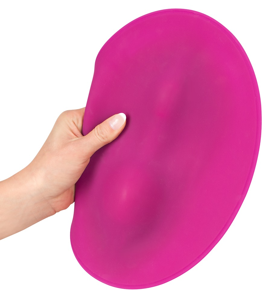 Eine Hand hält eine ovale, magentafarbene Silikonmatte vor weißem Hintergrund.