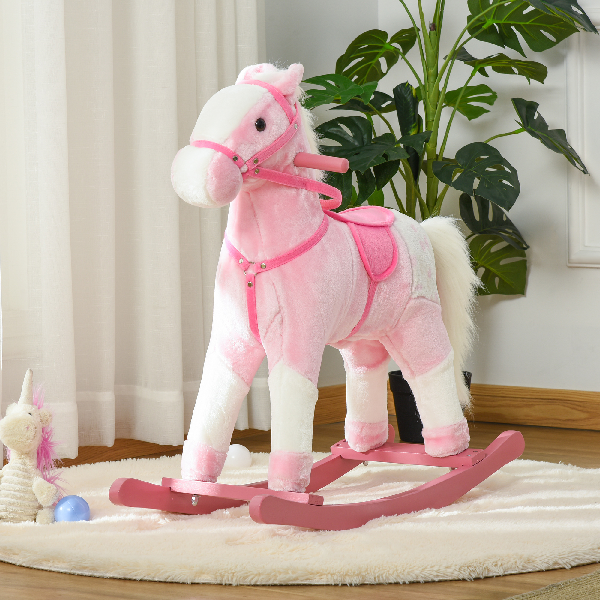 Un cavallo a dondolo di peluche rosa e bianco si trova su un tappeto soffice, con una pianta in vaso vicina.