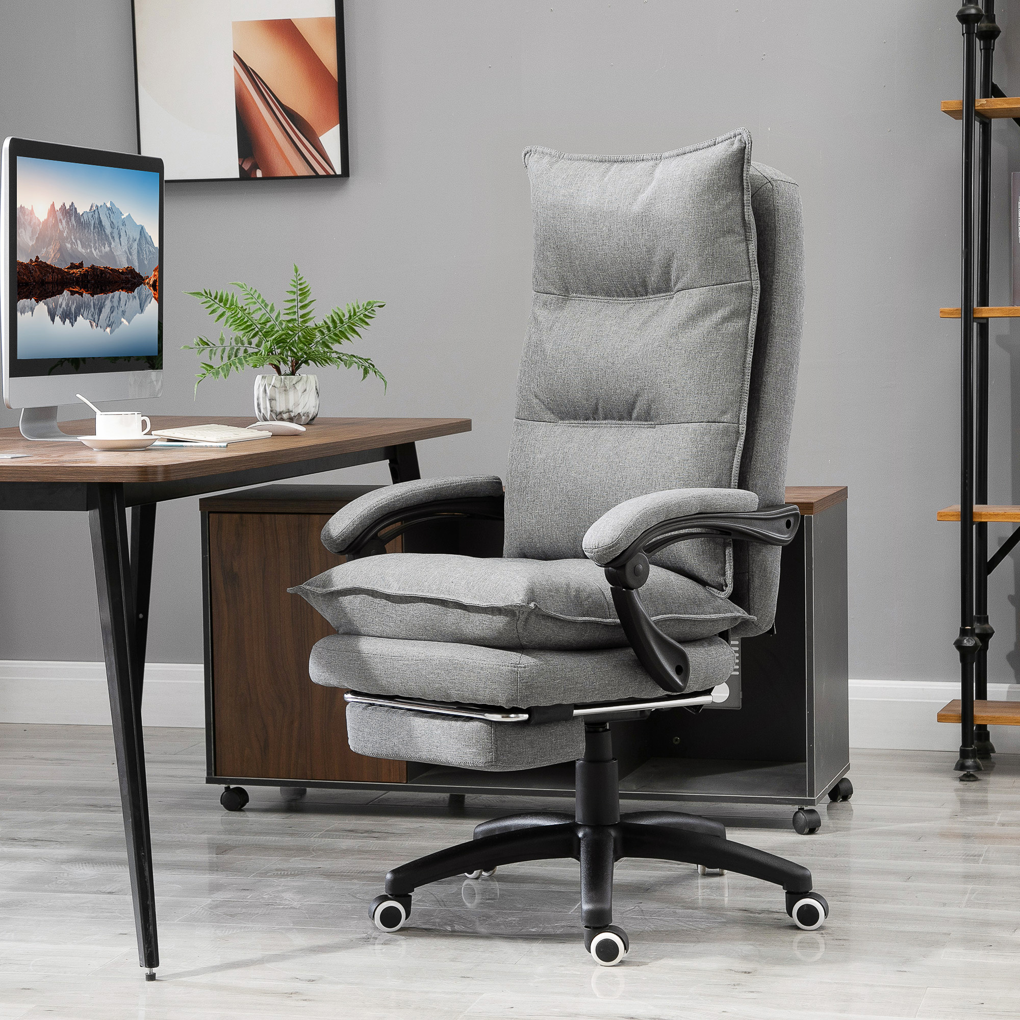 Una sedia da ufficio ergonomica grigia con poggiapiedi e cuscino si trova davanti a una scrivania.