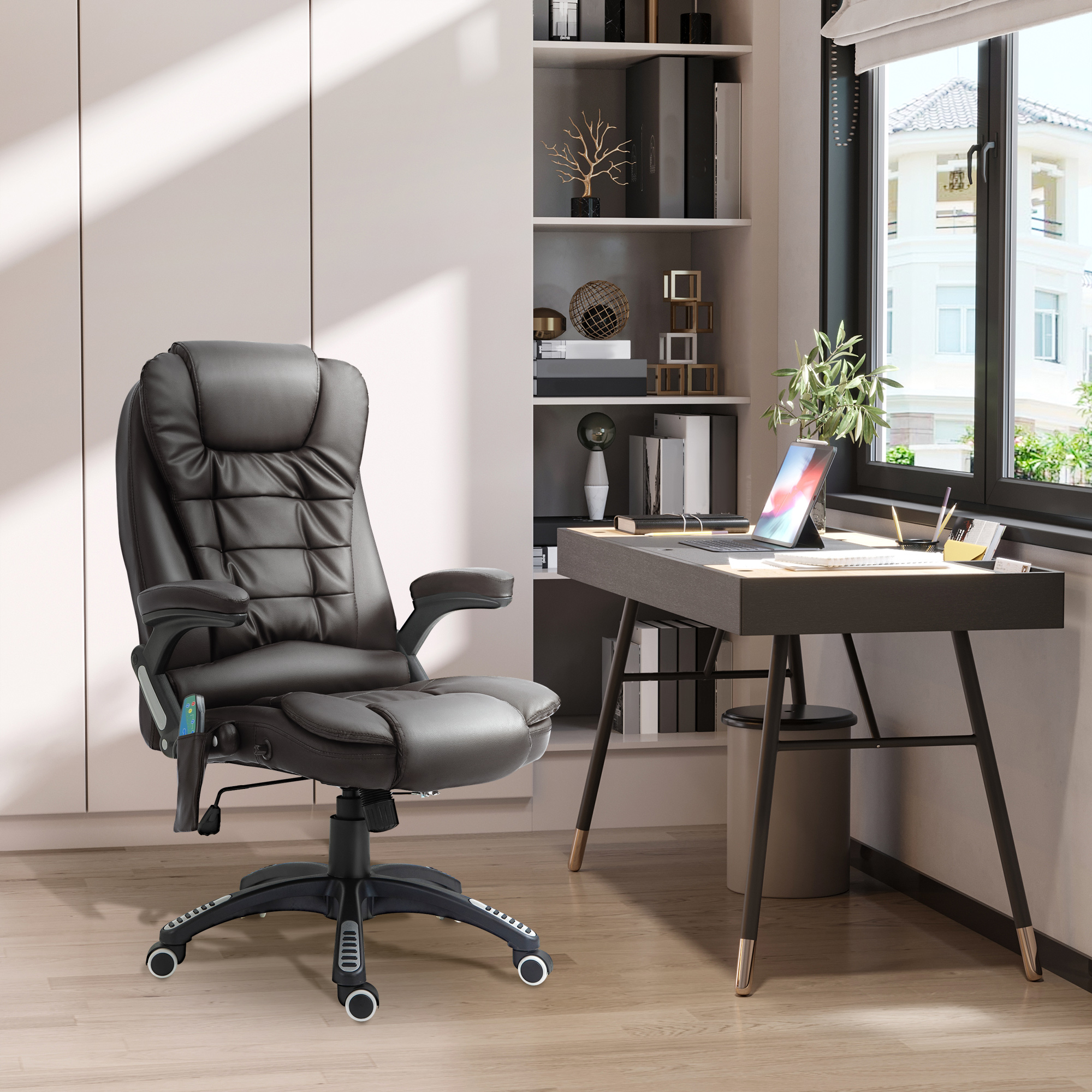 Una sedia ergonomica in pelle nera davanti a una scrivania in legno con laptop e scaffali.