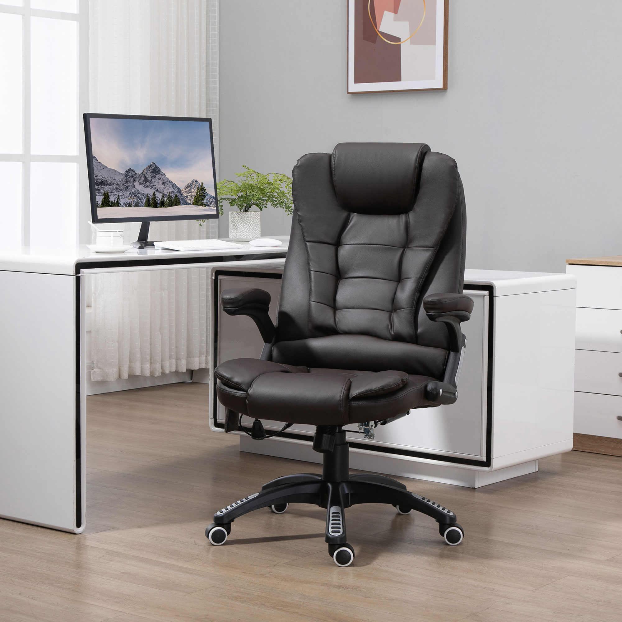 Una poltrona da ufficio in pelle marrone scuro in una stanza luminosa con scrivania bianca e computer.