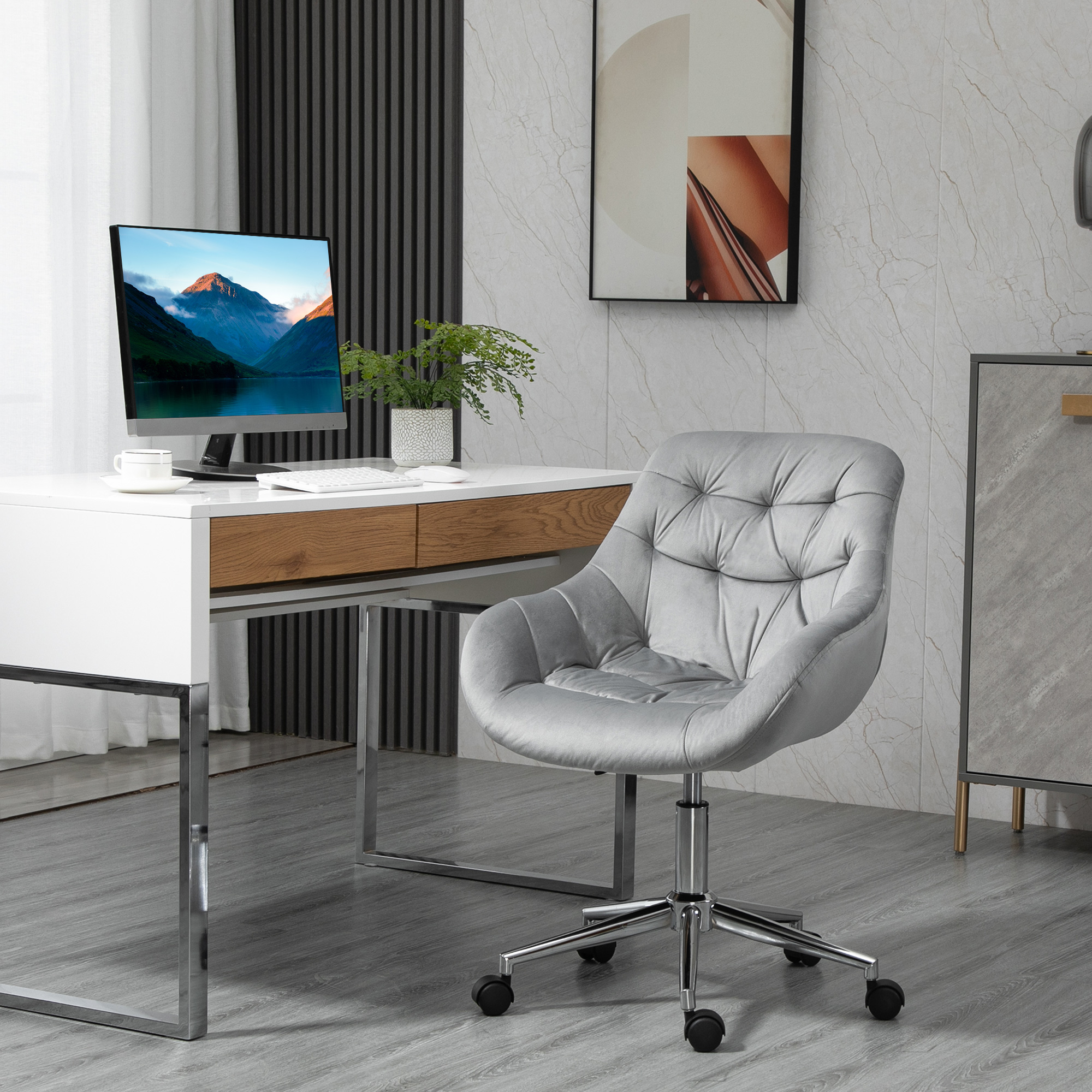 Ufficio moderno con sedia da scrivania grigia capitonné, scrivania bianca, computer e quadro astratto.