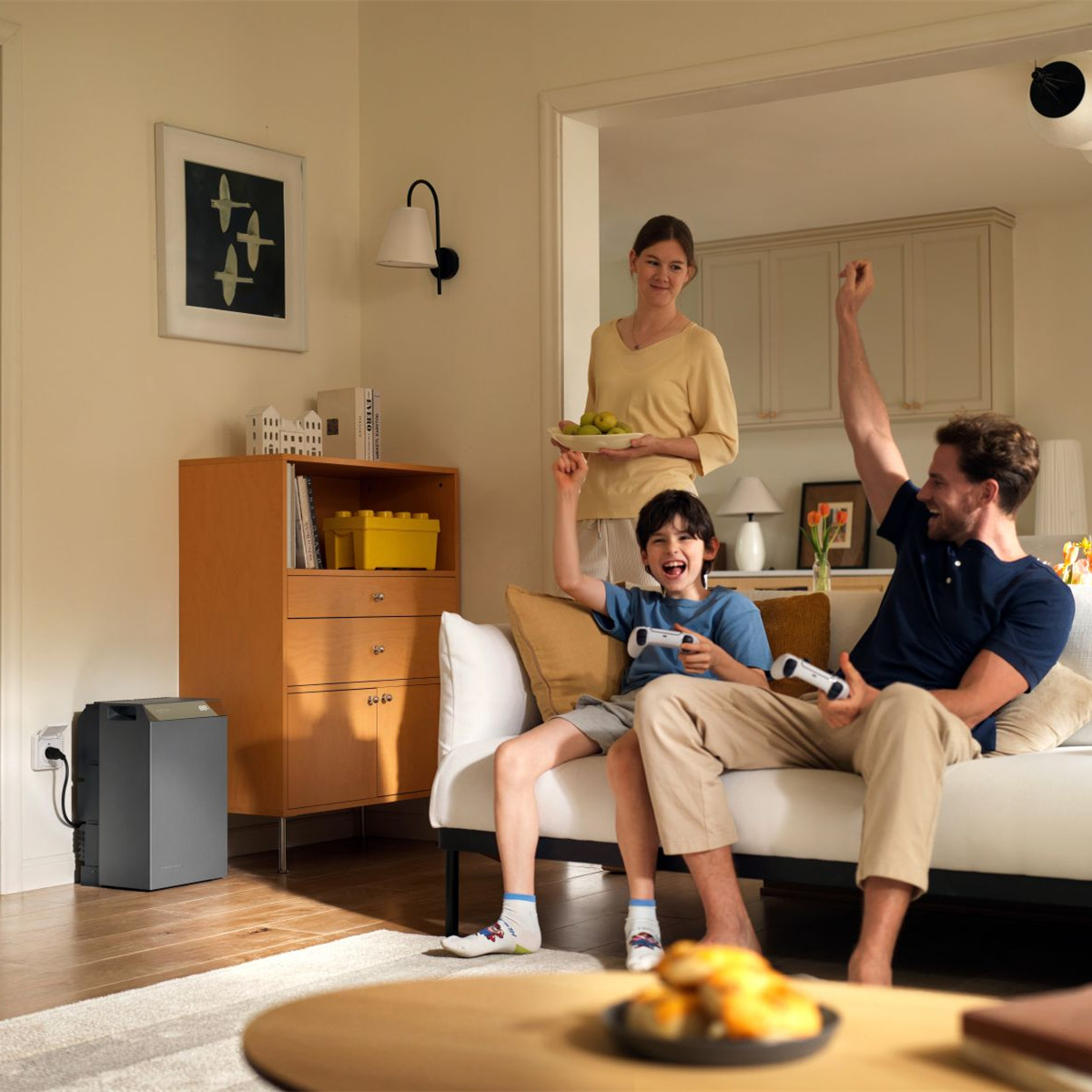 Ein Vater und Sohn spielen Videospiele auf einem Sofa, während eine Mutter zusieht.