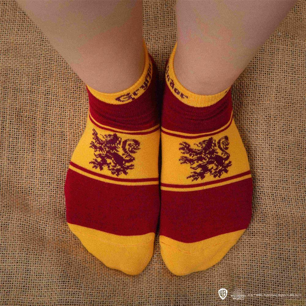 Pies con calcetines rojos y amarillos de Gryffindor sobre un fondo de yute marrón.