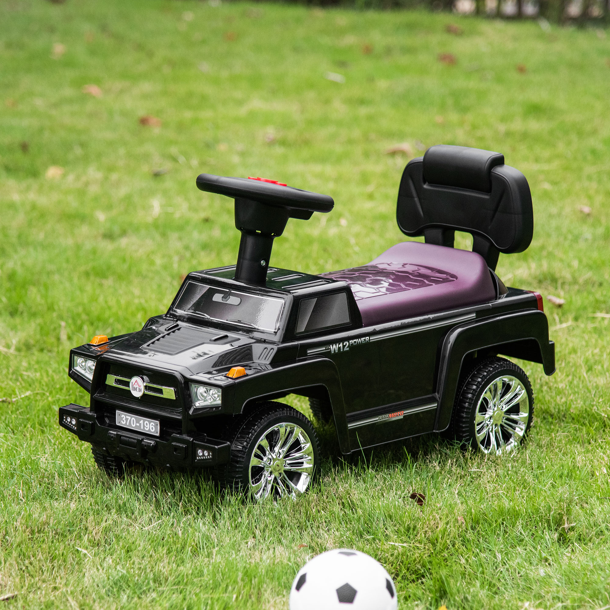 Un'auto giocattolo nera con ruote lucide e sedile viola su erba verde.
