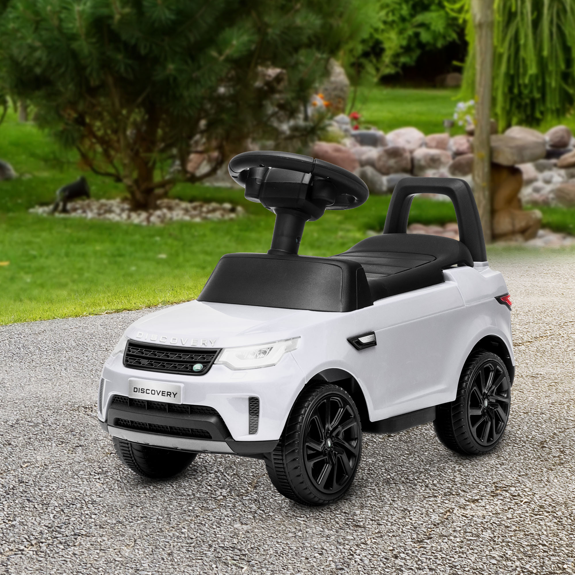 Un'auto cavalcabile bianca Land Rover Discovery si trova su un sentiero lastricato in un giardino.