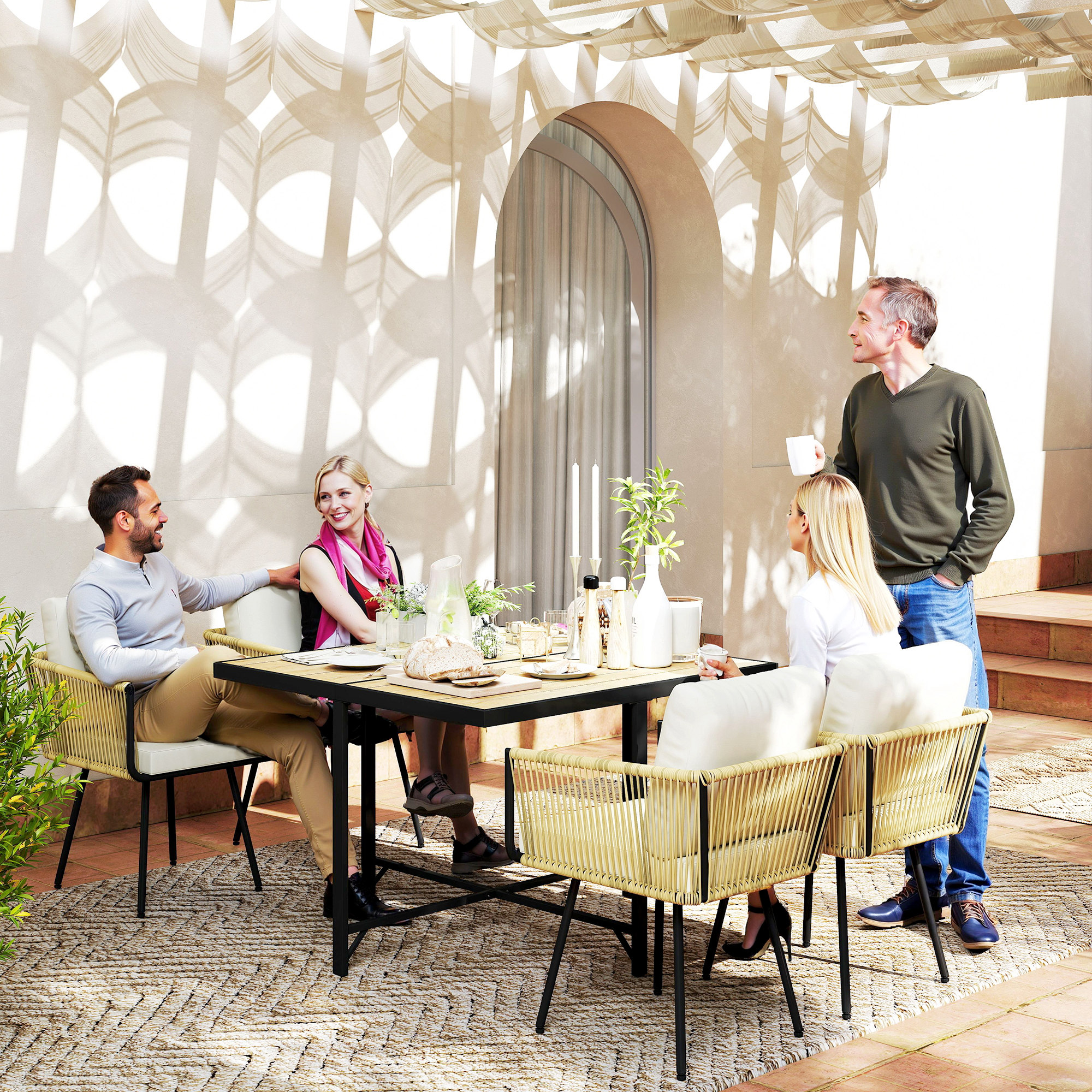 Cuatro personas se sientan y conversan en una mesa de comedor en un patio soleado.