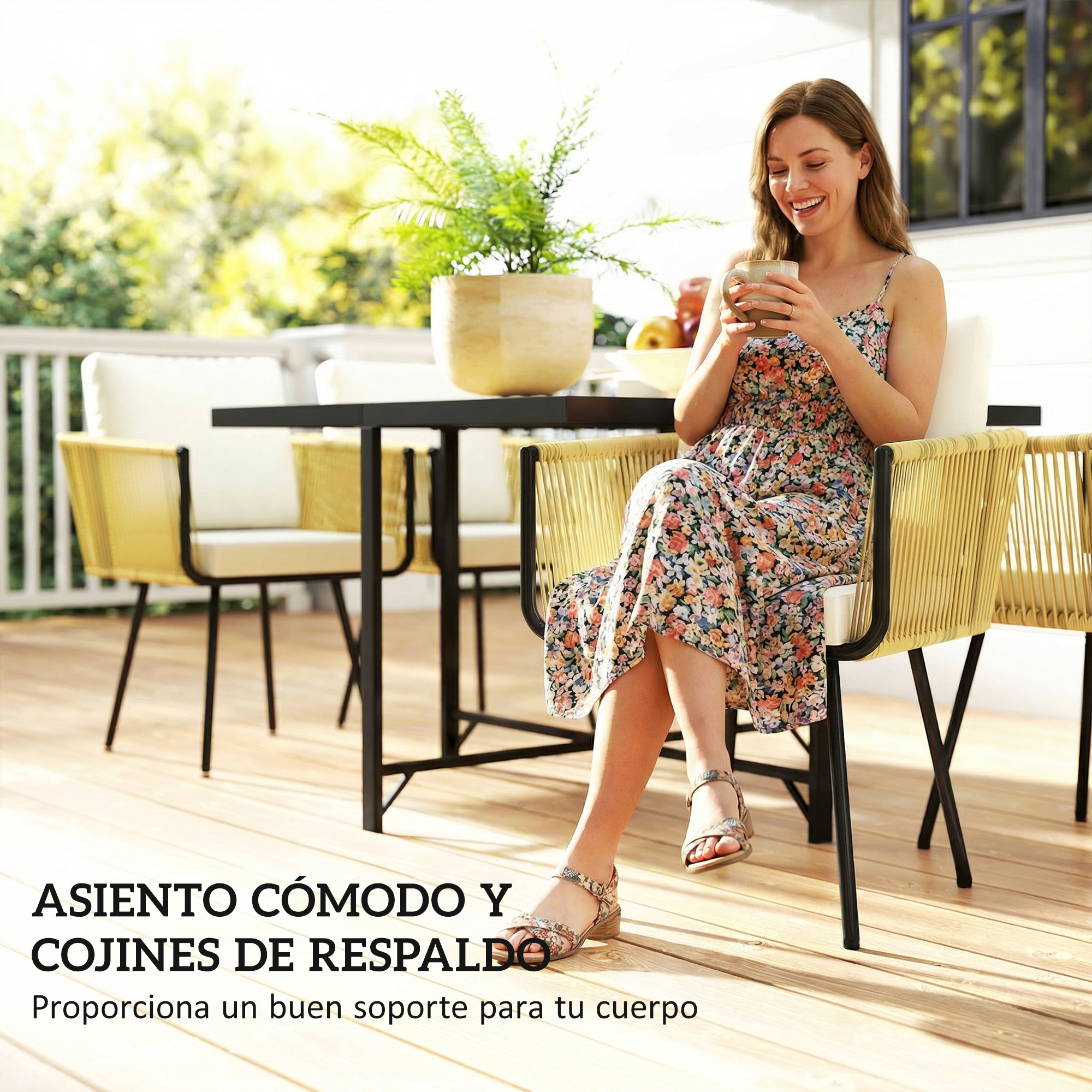 Una mujer con vestido floral está sentada en una silla en una terraza de madera soleada, sosteniendo una taza.