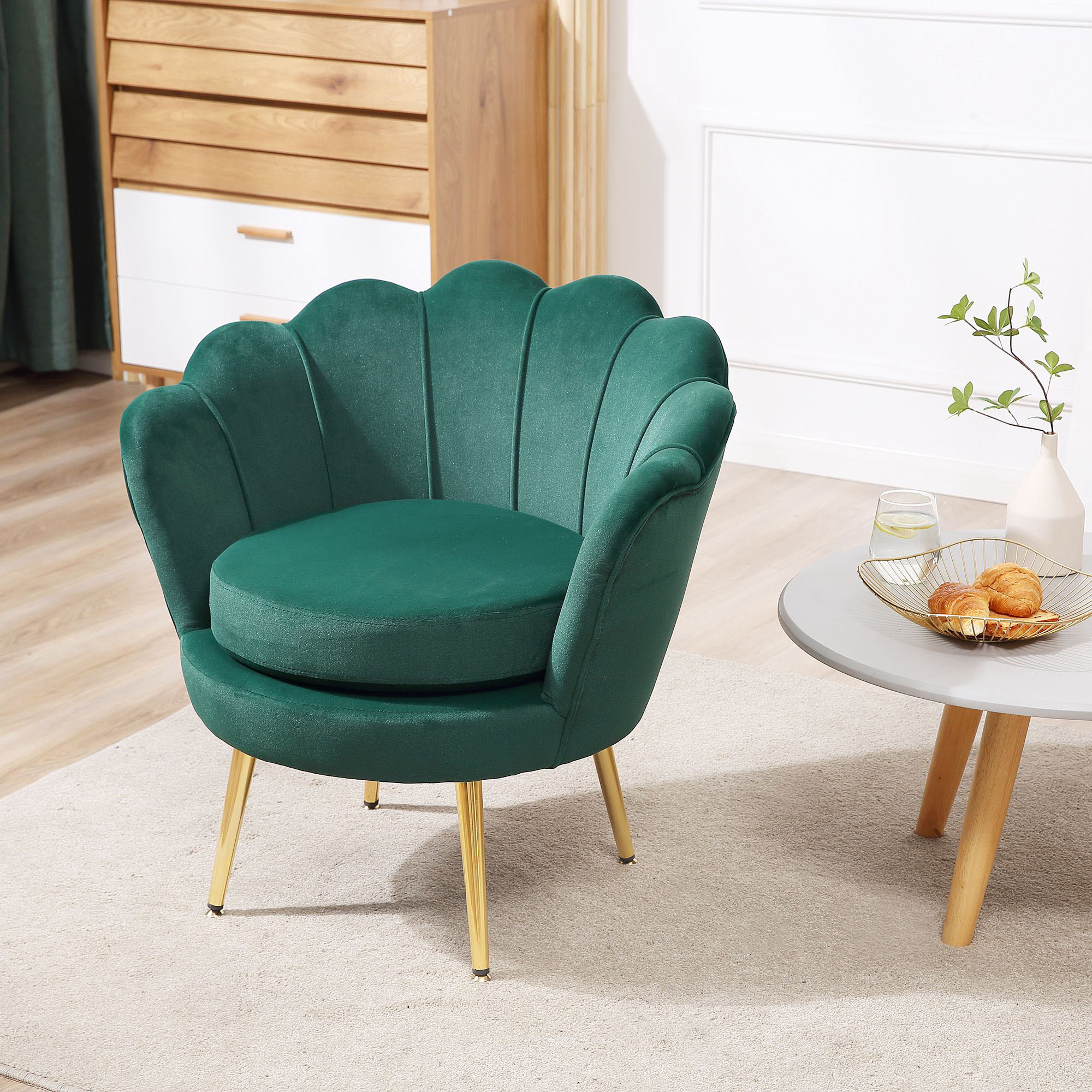 Una poltrona in velluto verde con gambe dorate su un tappeto.