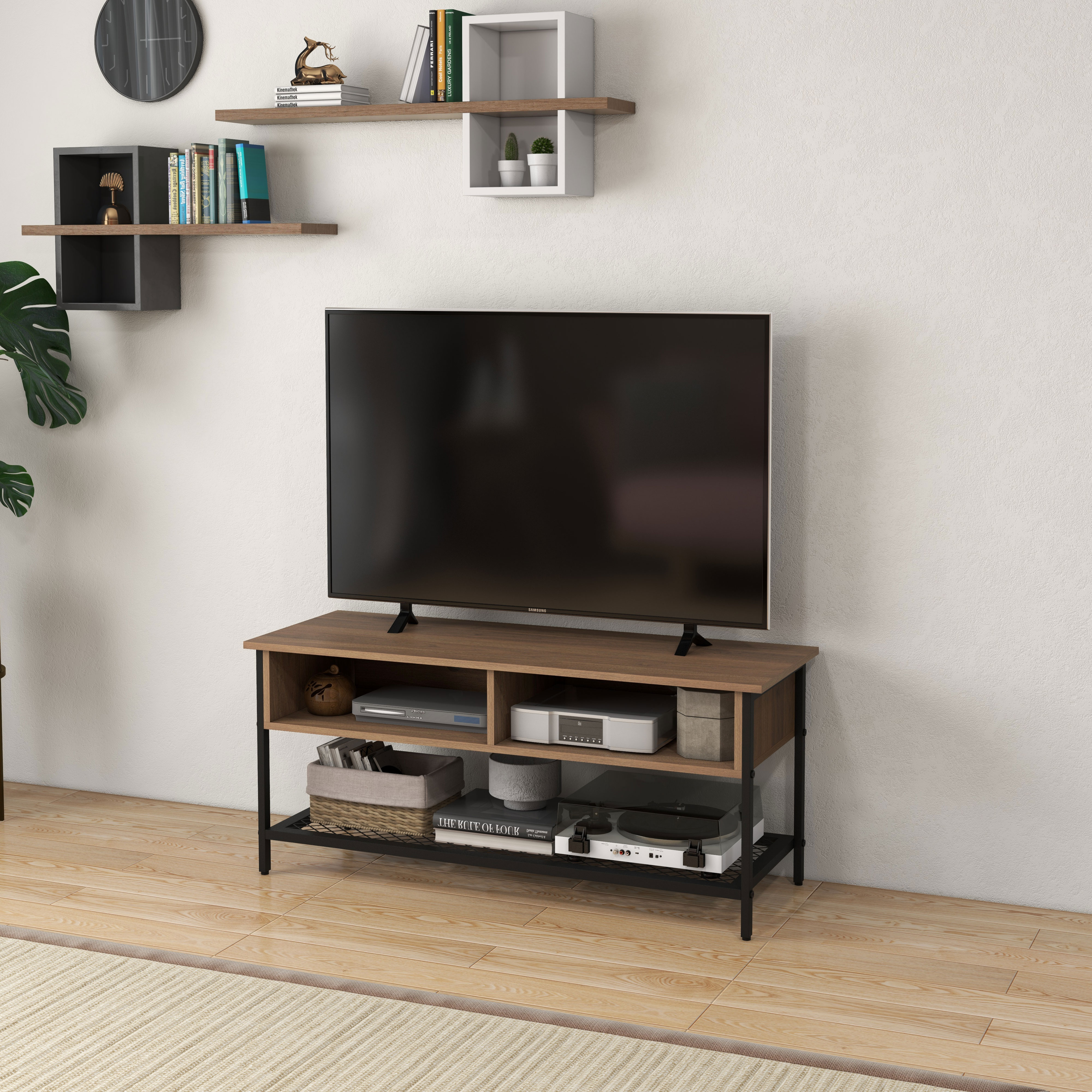 Una televisione su un mobile TV in legno e metallo contro una parete bianca con ripiani sospesi.