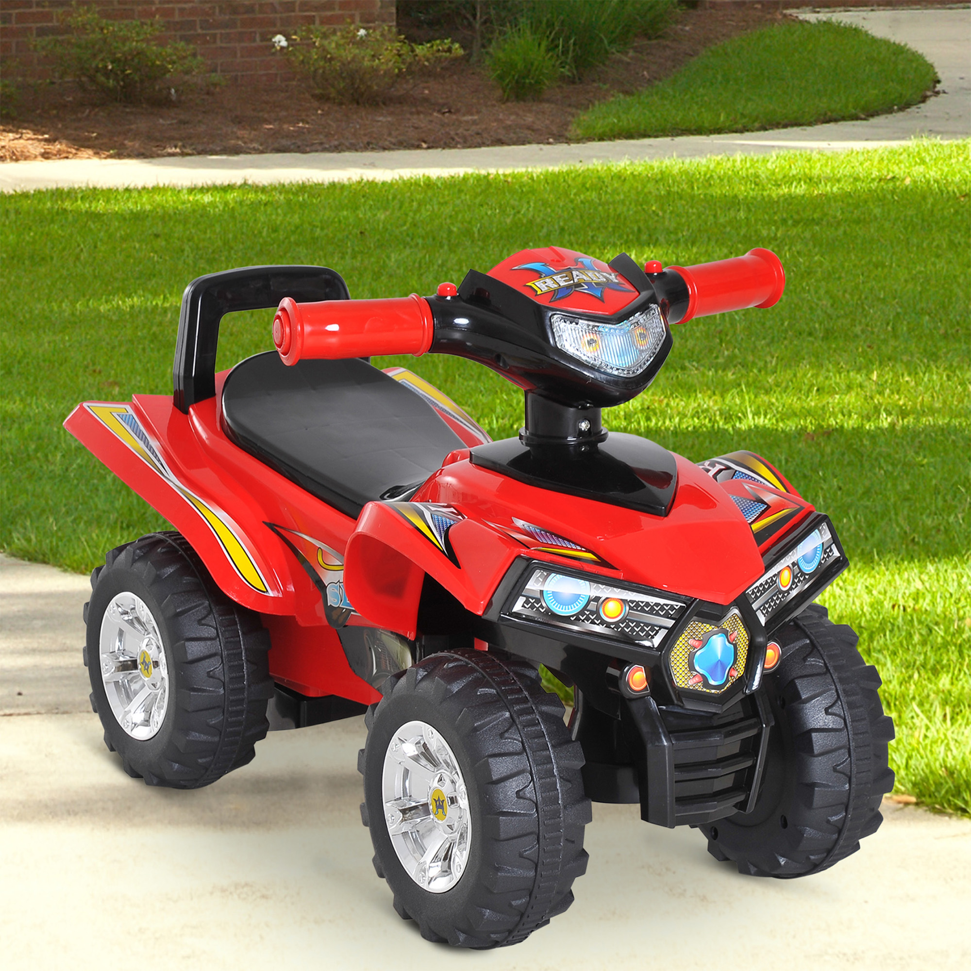 Un quad giocattolo rosso si trova su un marciapiede davanti all'erba verde e una casa in mattoni.