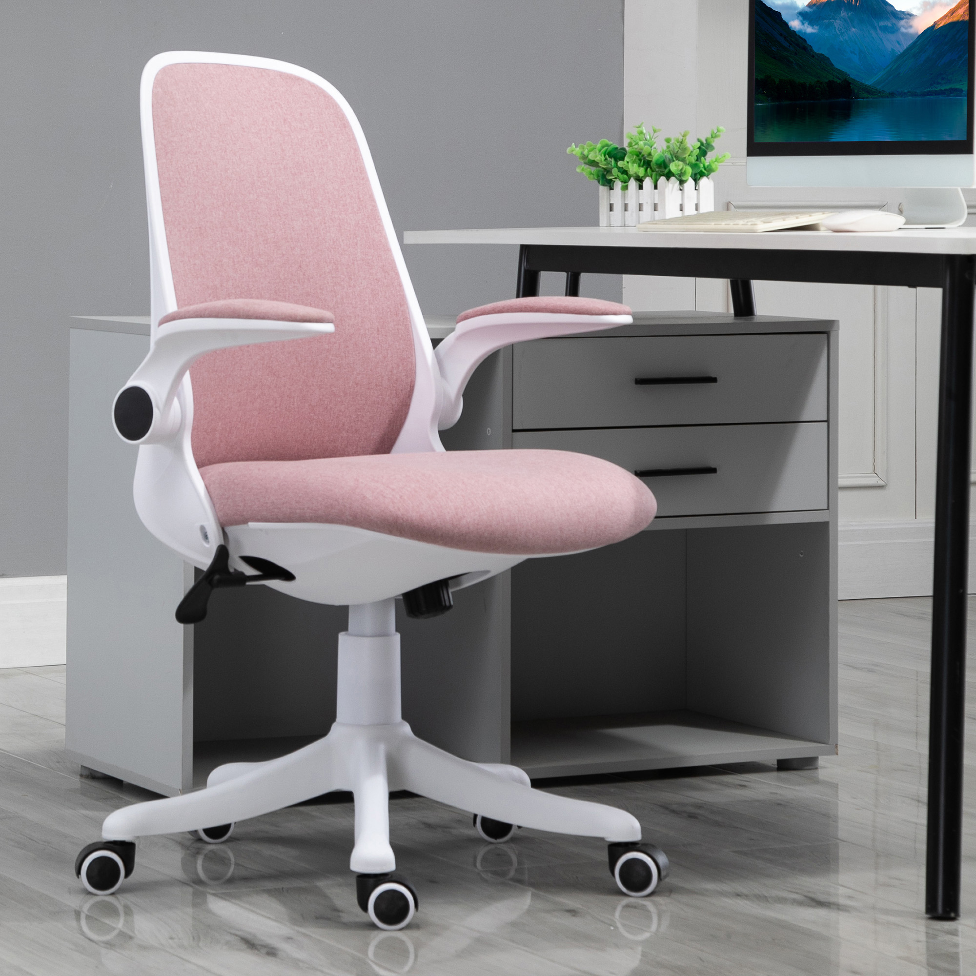 Una sedia da ufficchio ergonomica rosa e bianca è posizionata davanti a una scrivania grigia con computer.