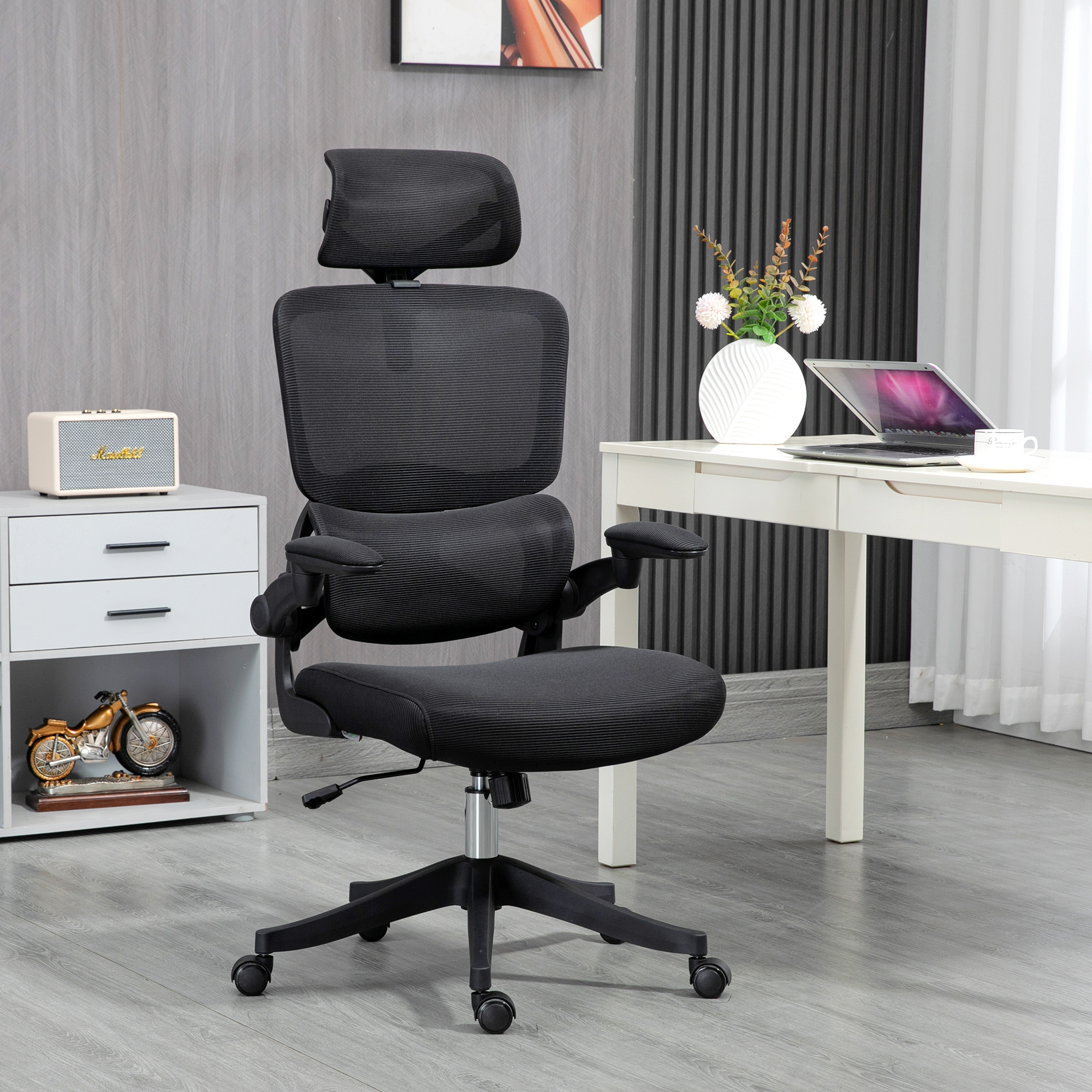 Una sedia da ufficio ergonomica in rete nera in una stanza moderna con scrivania bianca.