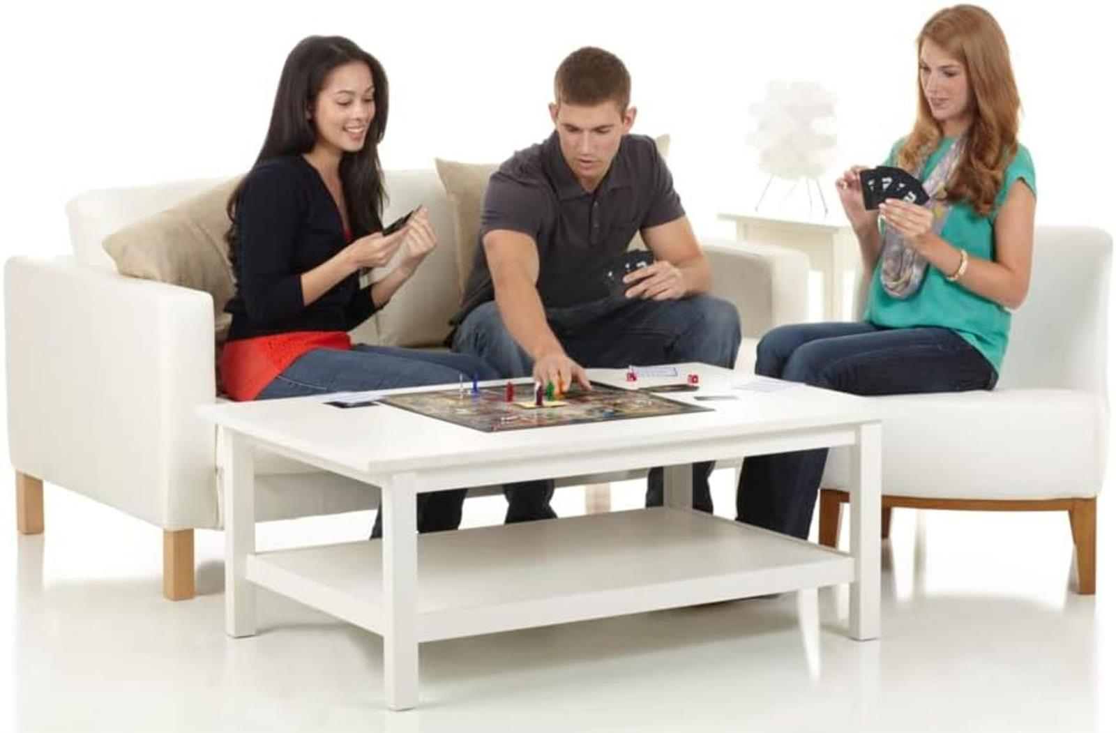 Drei junge Erwachsene sitzen in einem hellen Wohnzimmer und spielen ein Brettspiel.