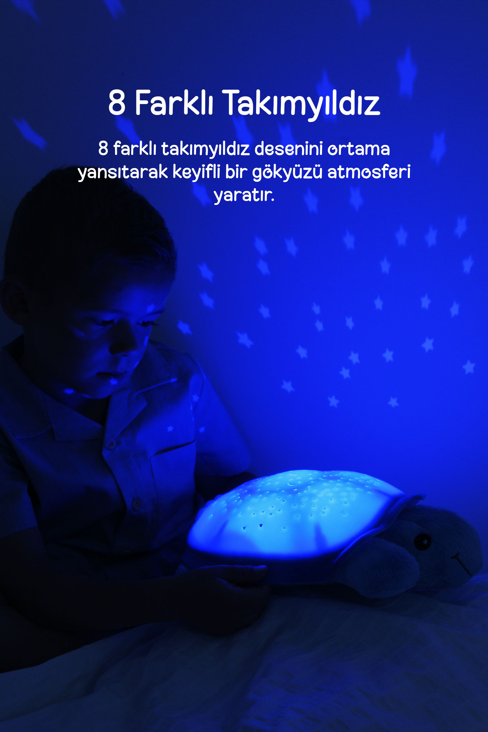 Bir çocuk duvara yıldız yansıtan mavi ışıklı bir kaplumbağa lamba tutuyor.