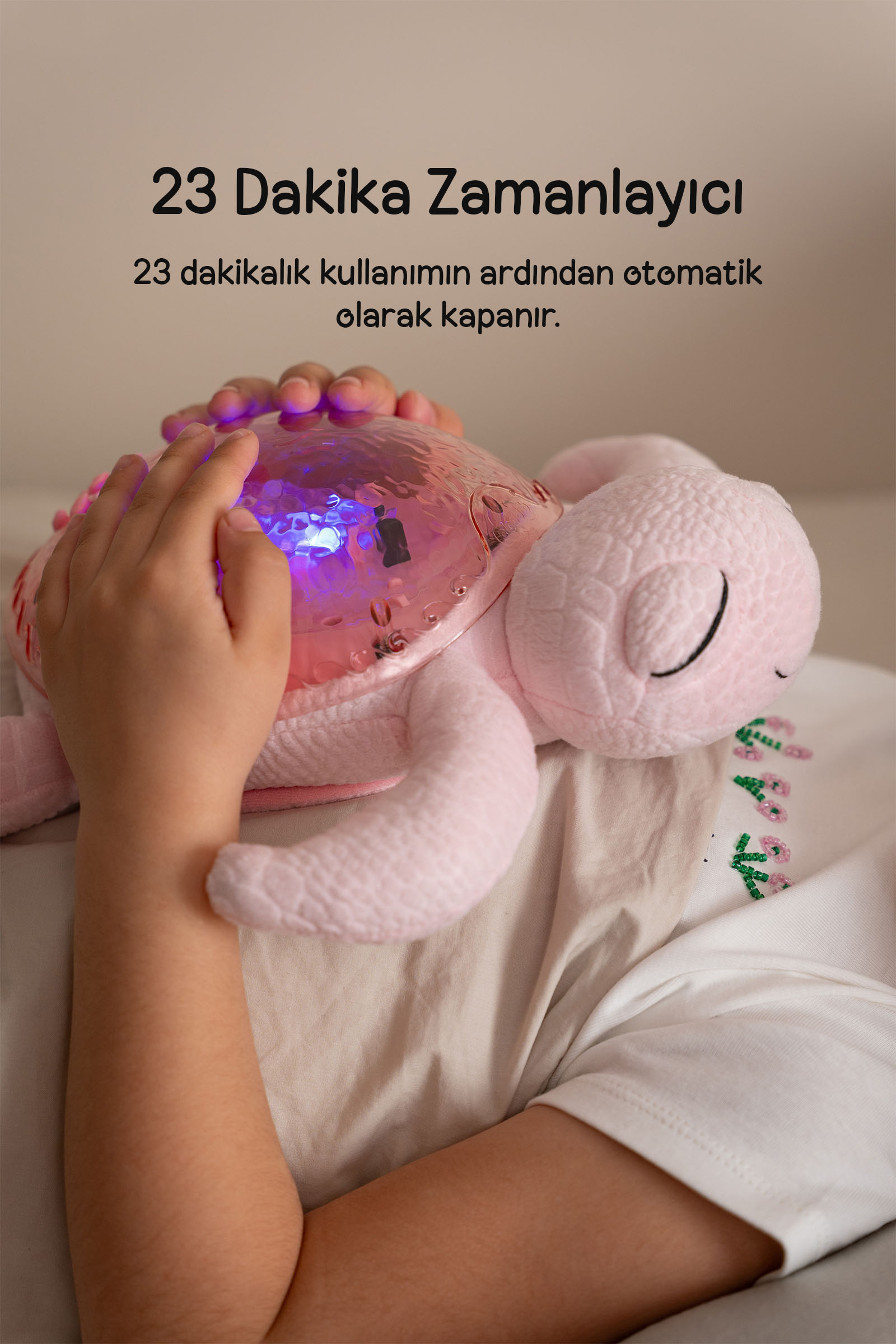 Bir çocuk, parlayan kabuğa sahip pembe pelüş bir kaplumbağayı tutuyor.