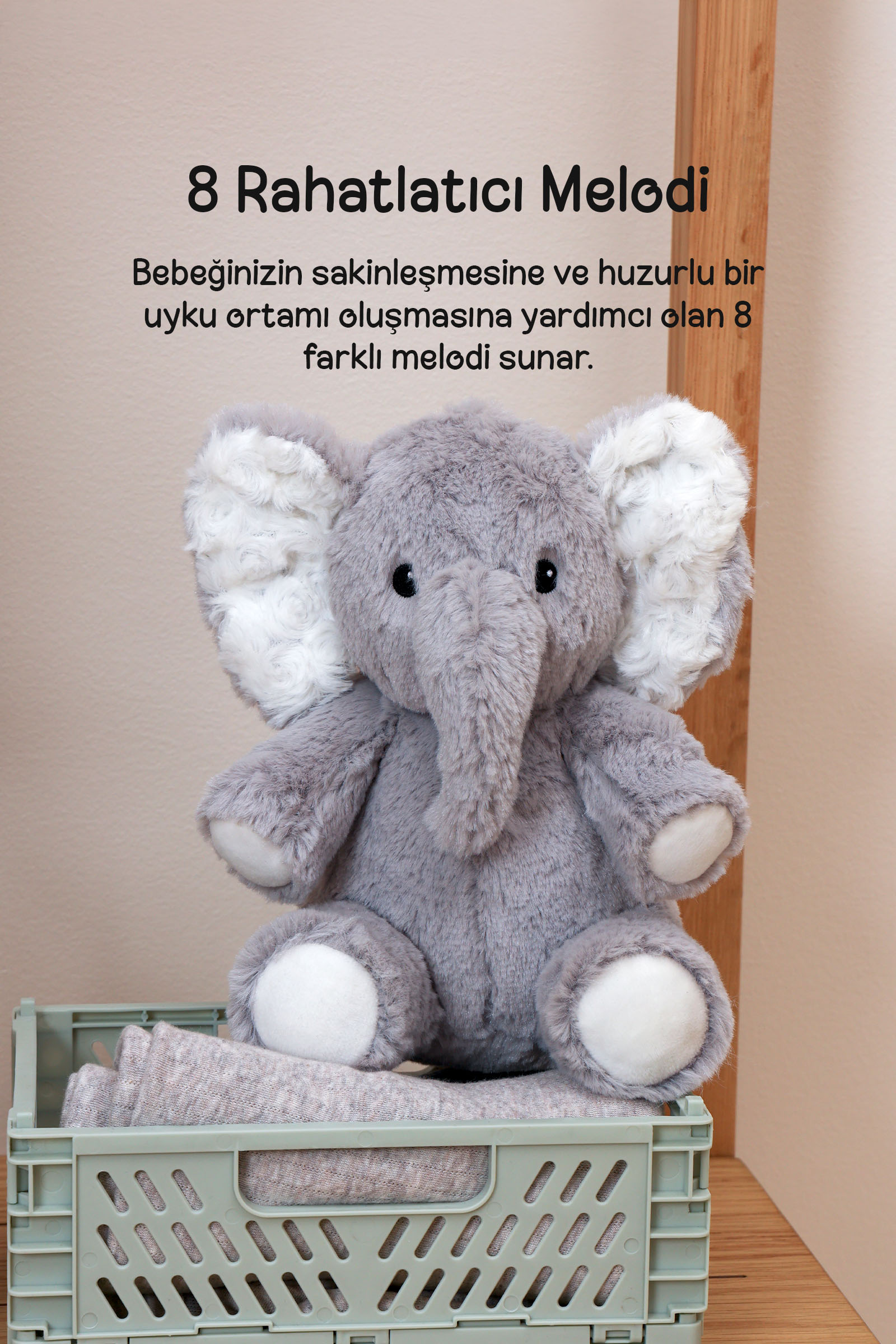 Ahşap yüzey üzerindeki yeşil kutuda oturan gri peluş fil. Üst kısımda Türkçe yazılar bulunuyor.