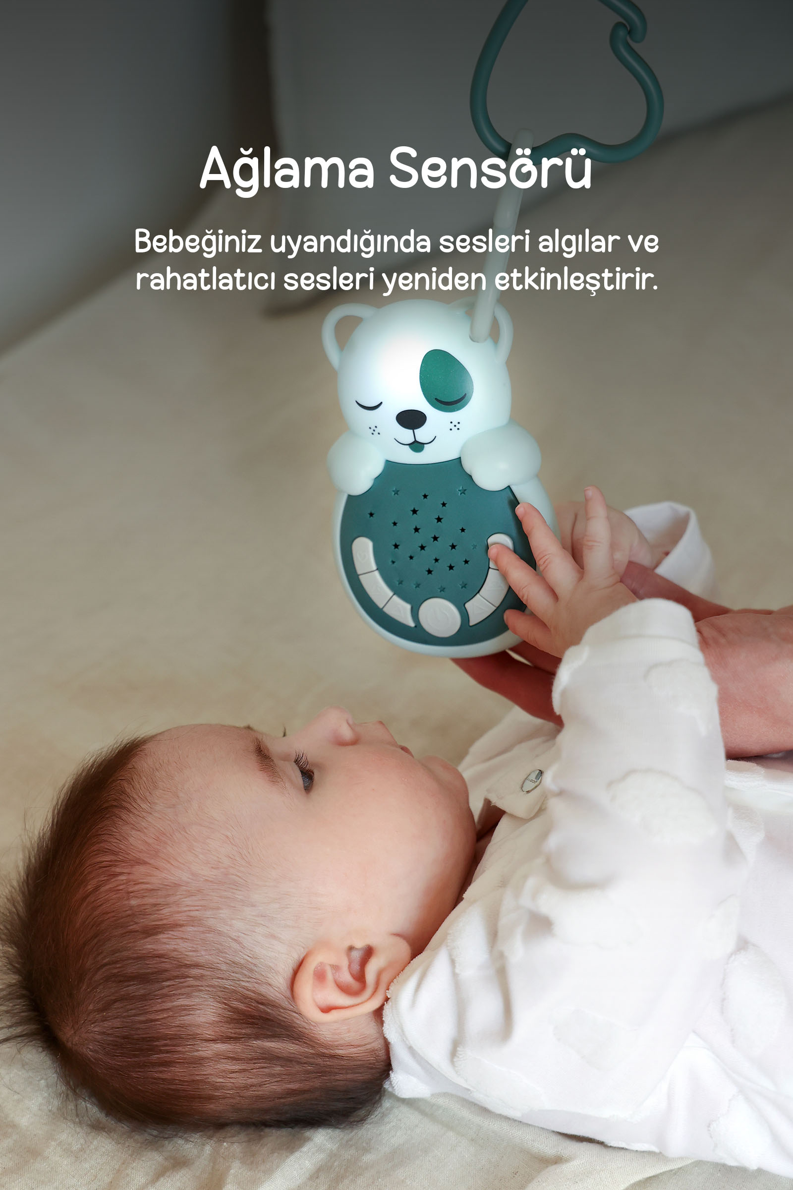 Sırtı üstü yatan bir bebek, ortasında metin olan ayı şekilli gece lambasına bakıyor.