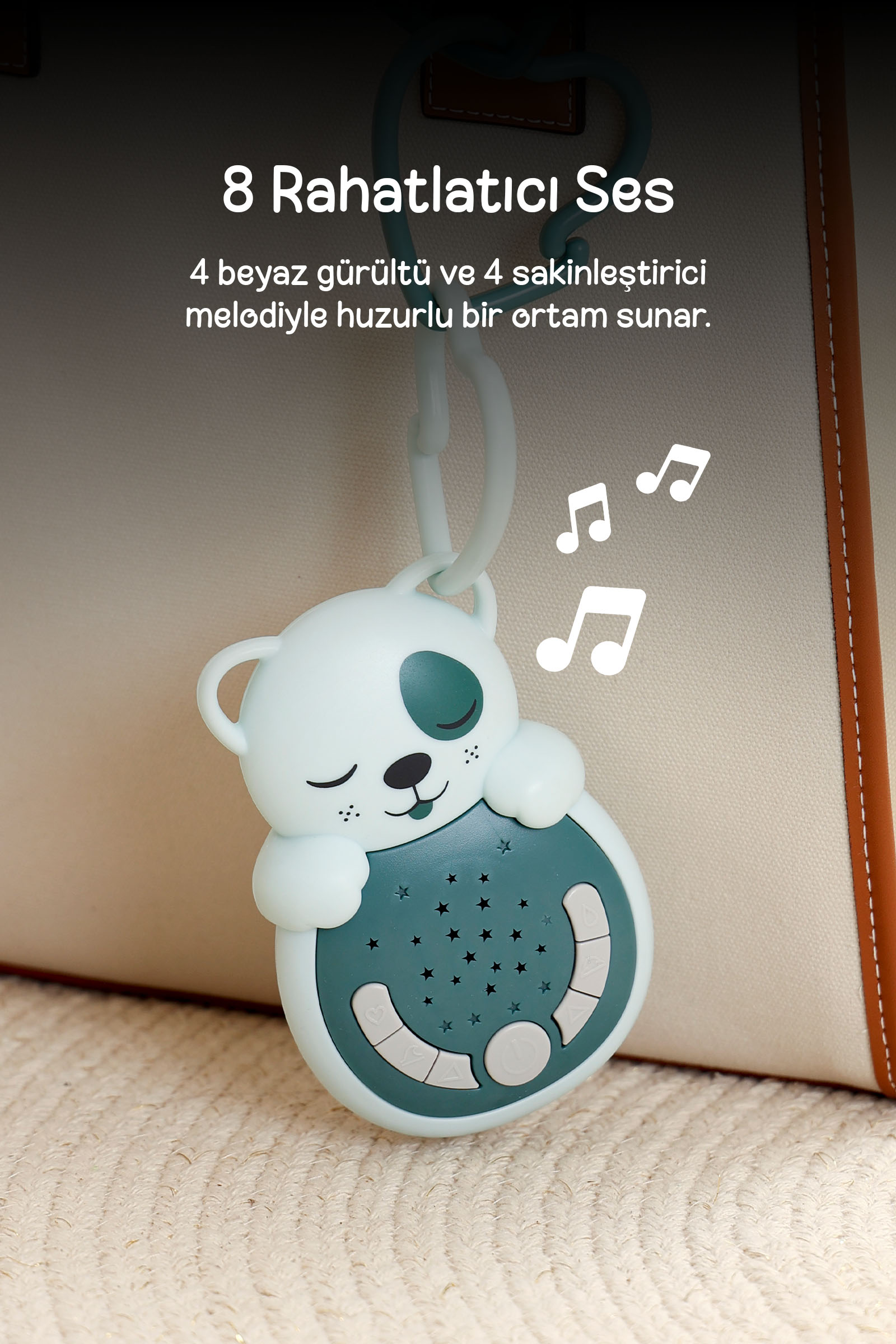 Yıldız desenli turkuaz panda bebek ses makinesi açık renkli çantaya asılı duruyor ve müzik notaları sembolleri var.