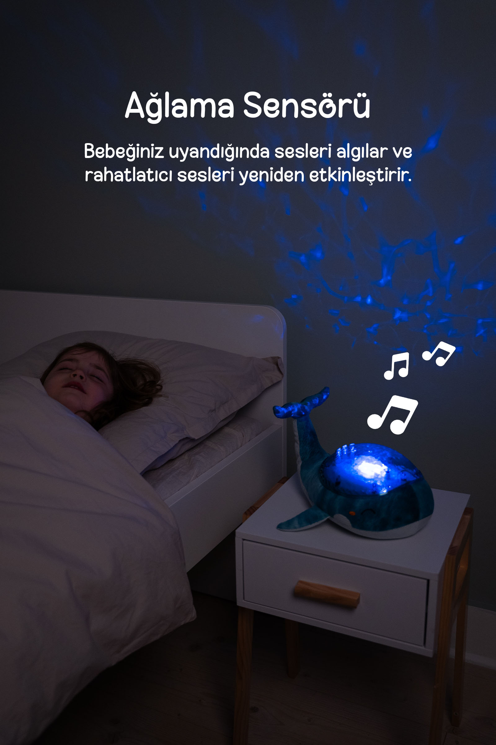 Bir çocuk, müzik notaları ve projeksiyonlar gösteren mavi balina gece lambasının yanında yatıyor.