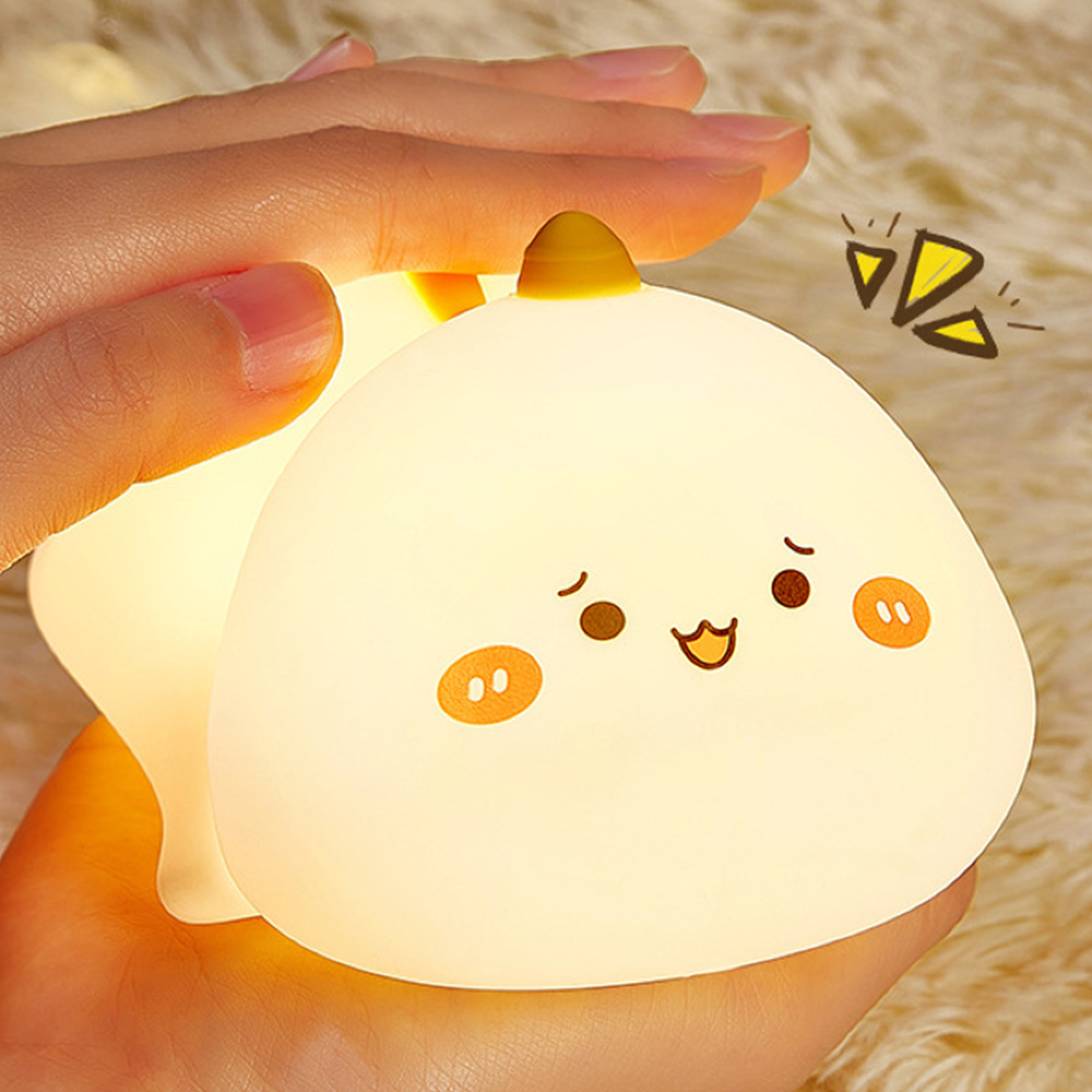Eine Hand hält eine süße, leuchtende weiße Nachtlampe mit einem niedlichen Gesicht auf flauschigem Hintergrund.
