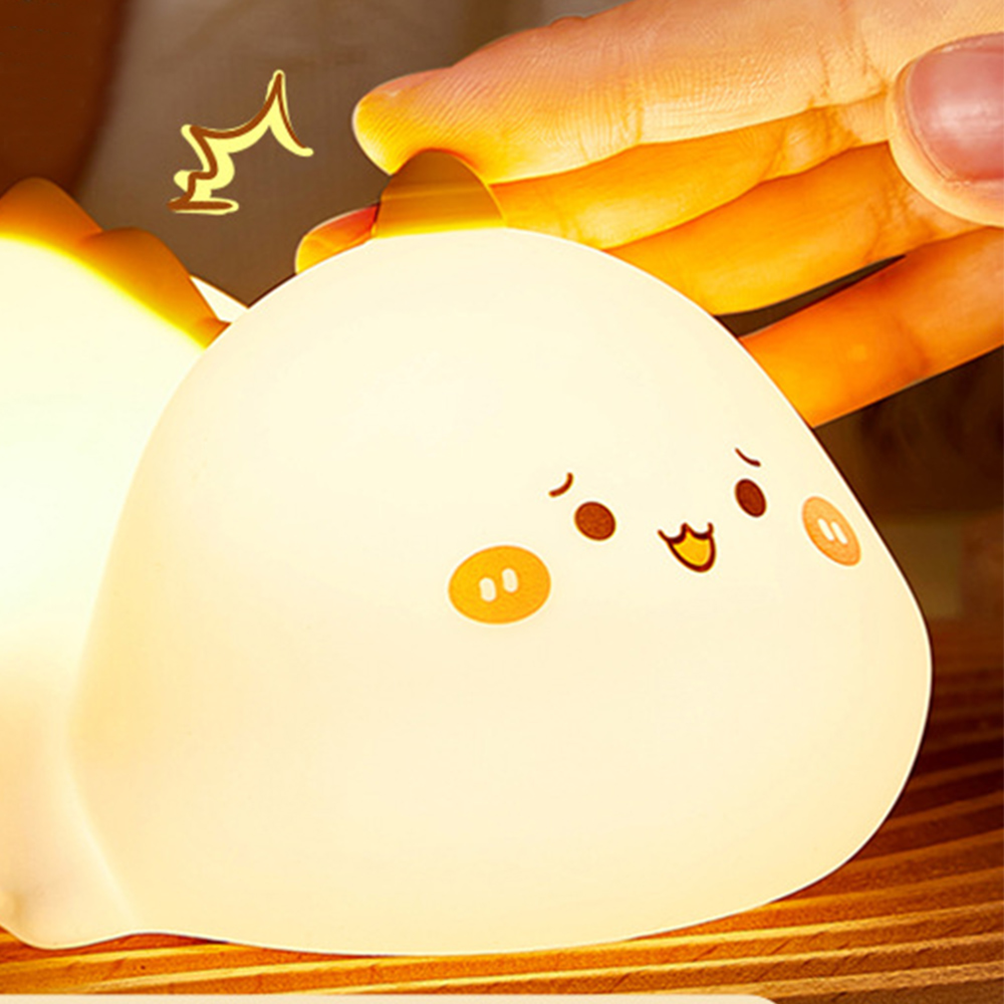 Eine Hand tippt auf eine niedliche, leuchtende Silikonlampe in Form einer Katze auf Holz.