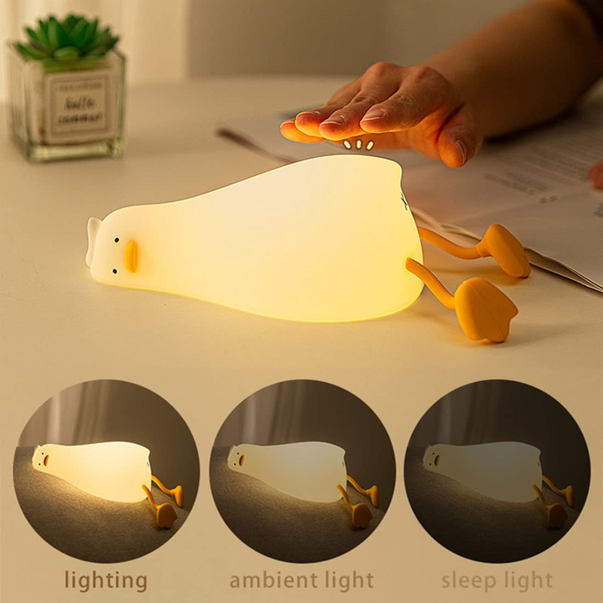 Eine Hand berührt eine weiche, gelb leuchtende Entenlampe auf einem Tisch mit drei Beleuchtungsmodi.
