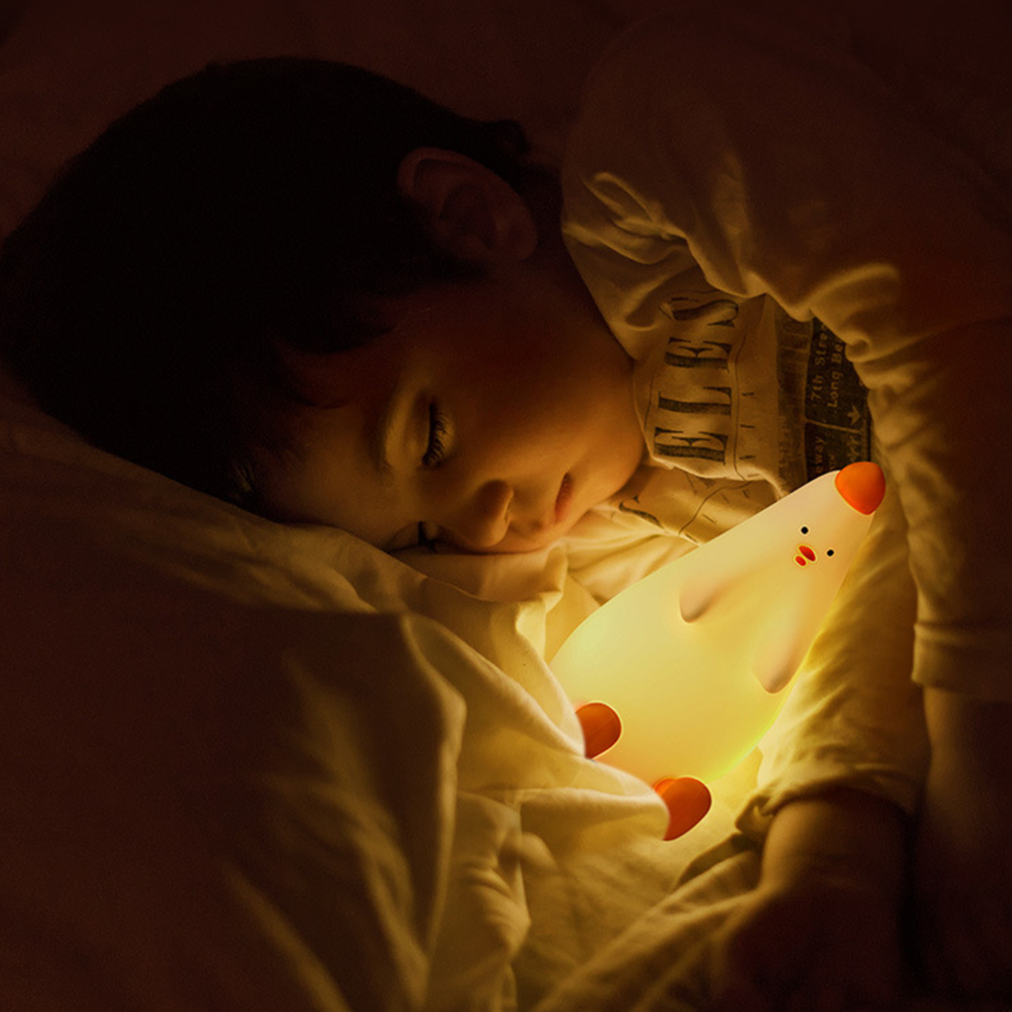 Ein Kind schläft friedlich im Bett und umarmt ein leuchtendes Entennachtlicht.