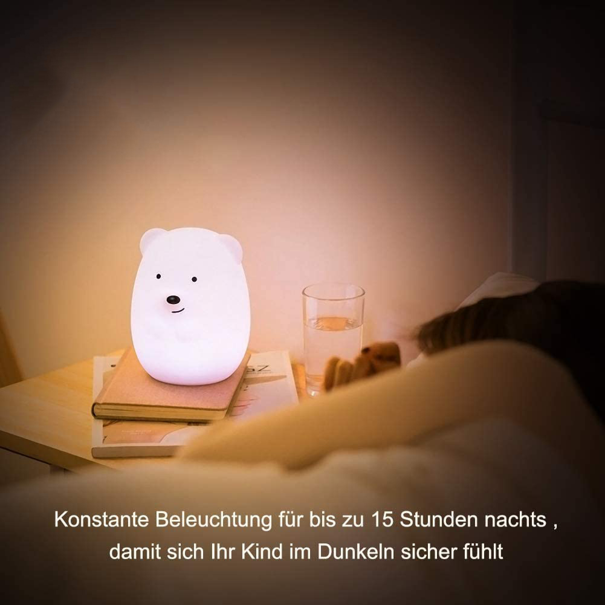 Ein kleines Bären-Nachtlicht leuchtet auf einem Nachttisch neben einem Glas Wasser, während ein Kind im Bett schläft.