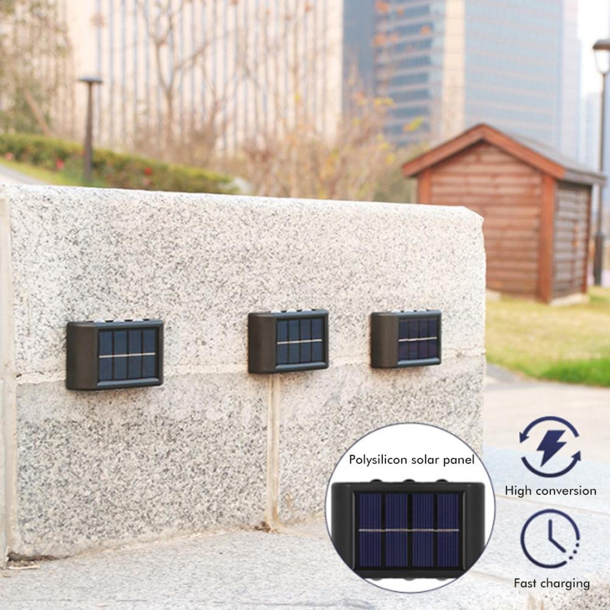 Drei kleine schwarze Solarleuchten sind an einer grauen Steinmauer im Freien befestigt.