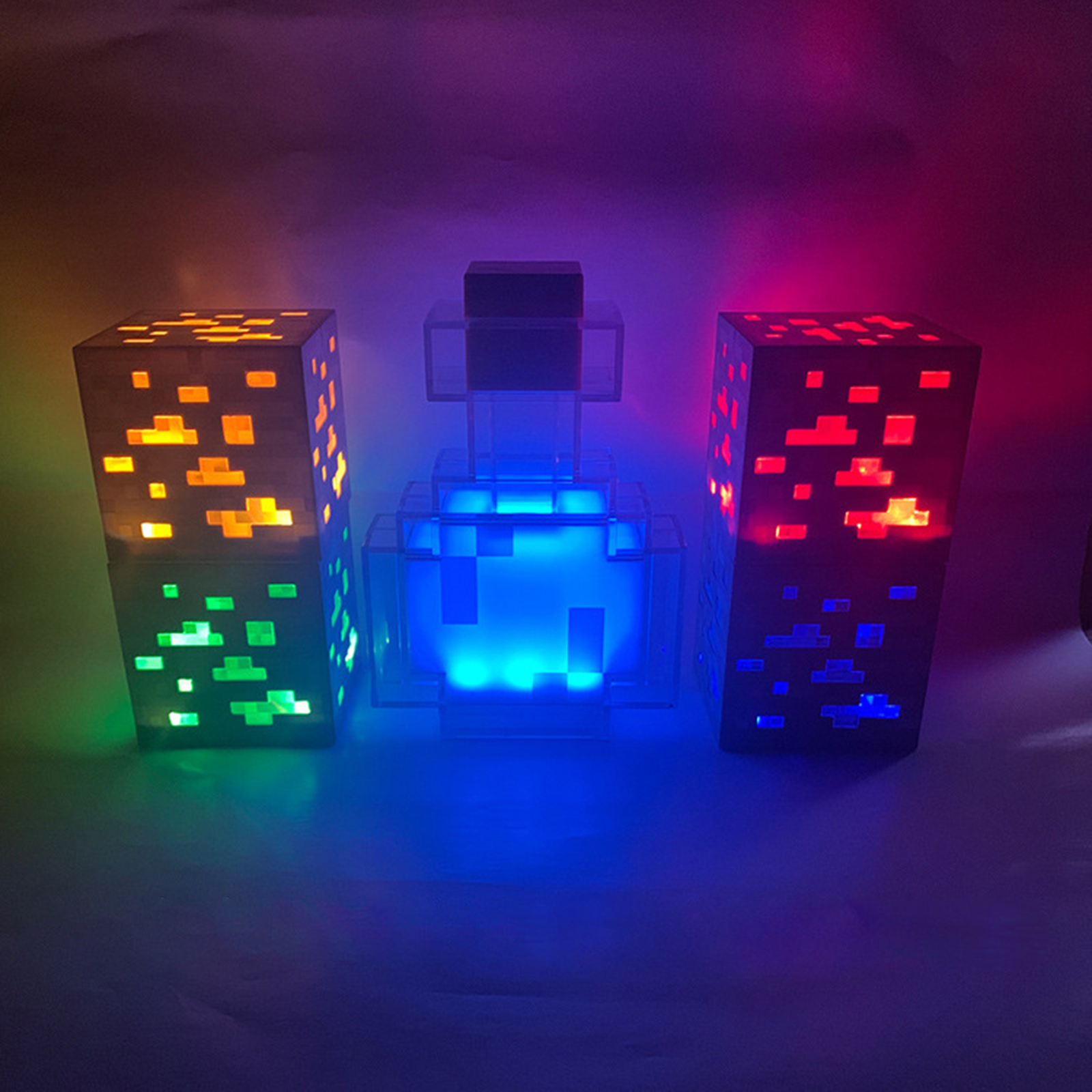 Drei beleuchtete Minecraft-Lampen in Form von Erzen und einer blauen Zaubertrankflasche stehen auf einer dunklen Fläche.