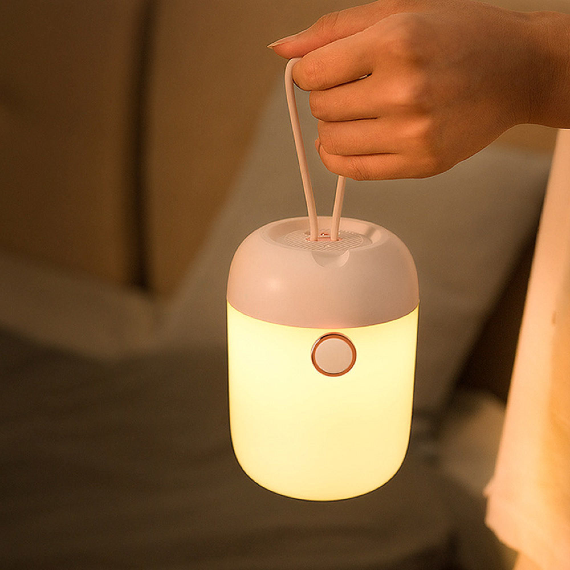 Eine Hand hält eine kleine weiße tragbare Nachtlampe mit warmem Licht.